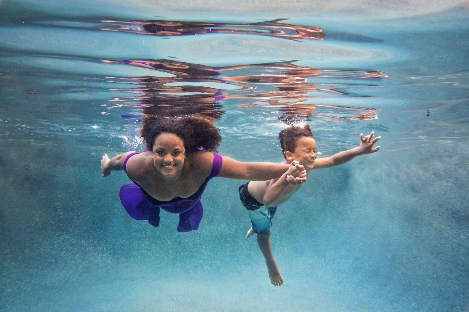 Underwater photography showing swimmers with colorful fabric creating artistic patterns.