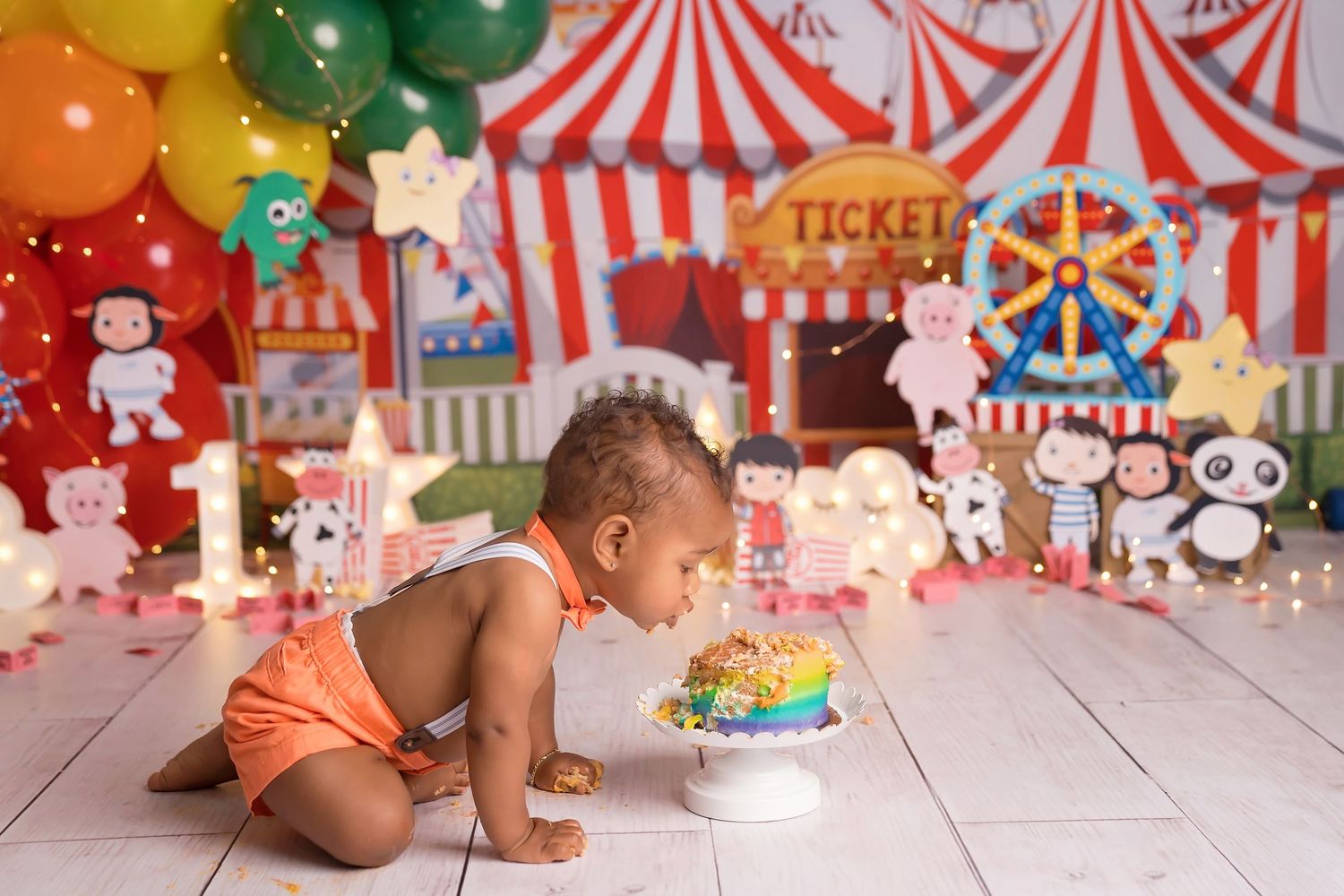 Circus-themed photo setup with bright balloons and red and white striped tent decorations.