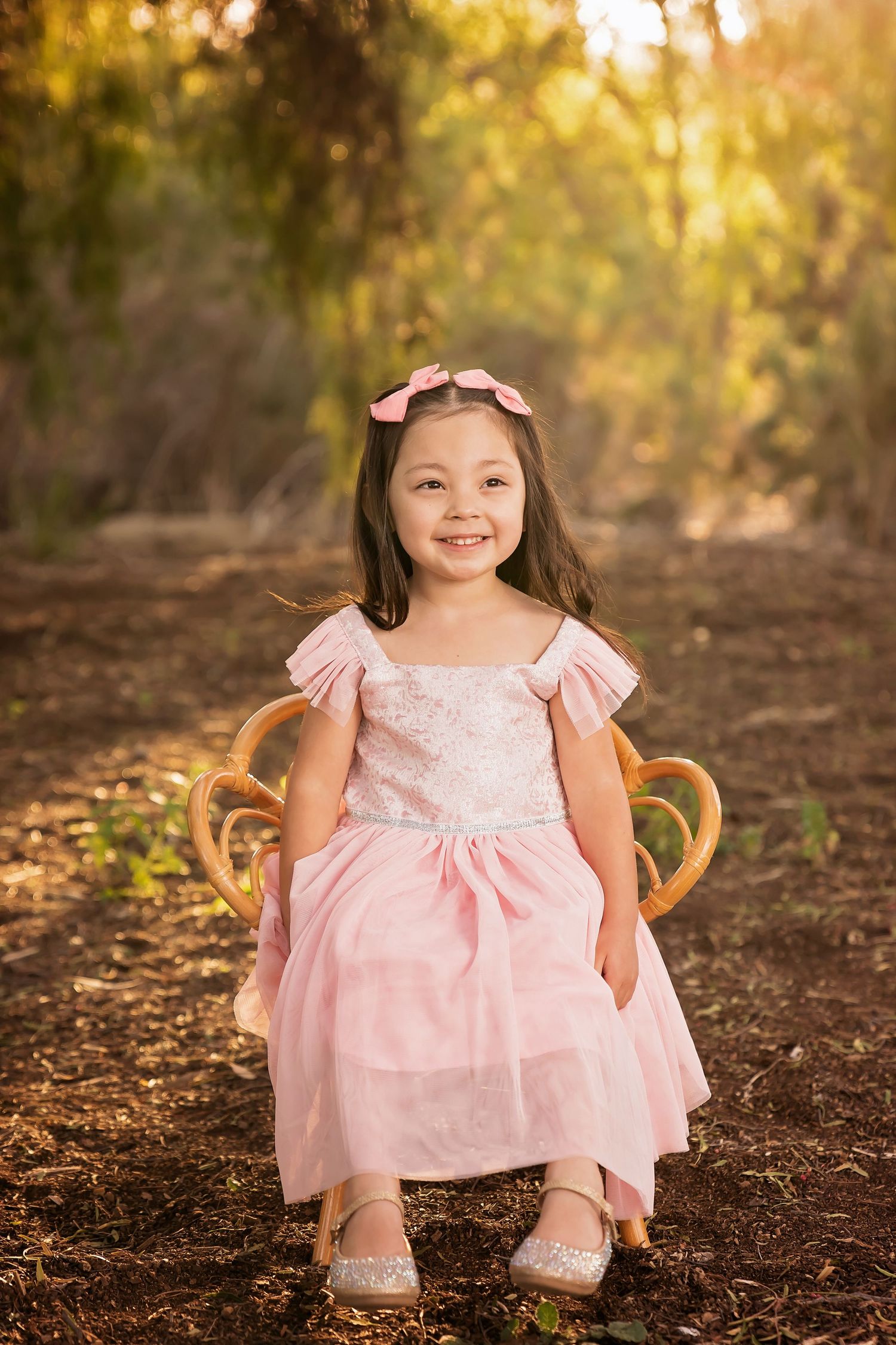 Child in a light pink dress posing outdoors in soft natural lighting