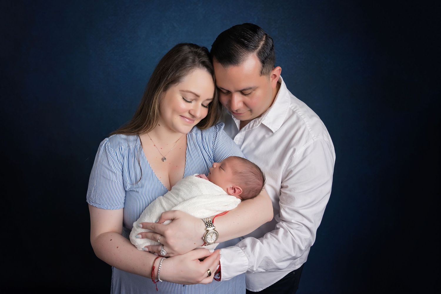 Professional family portrait series against dark blue background showing tender moments. San Diego Newborn Photographer