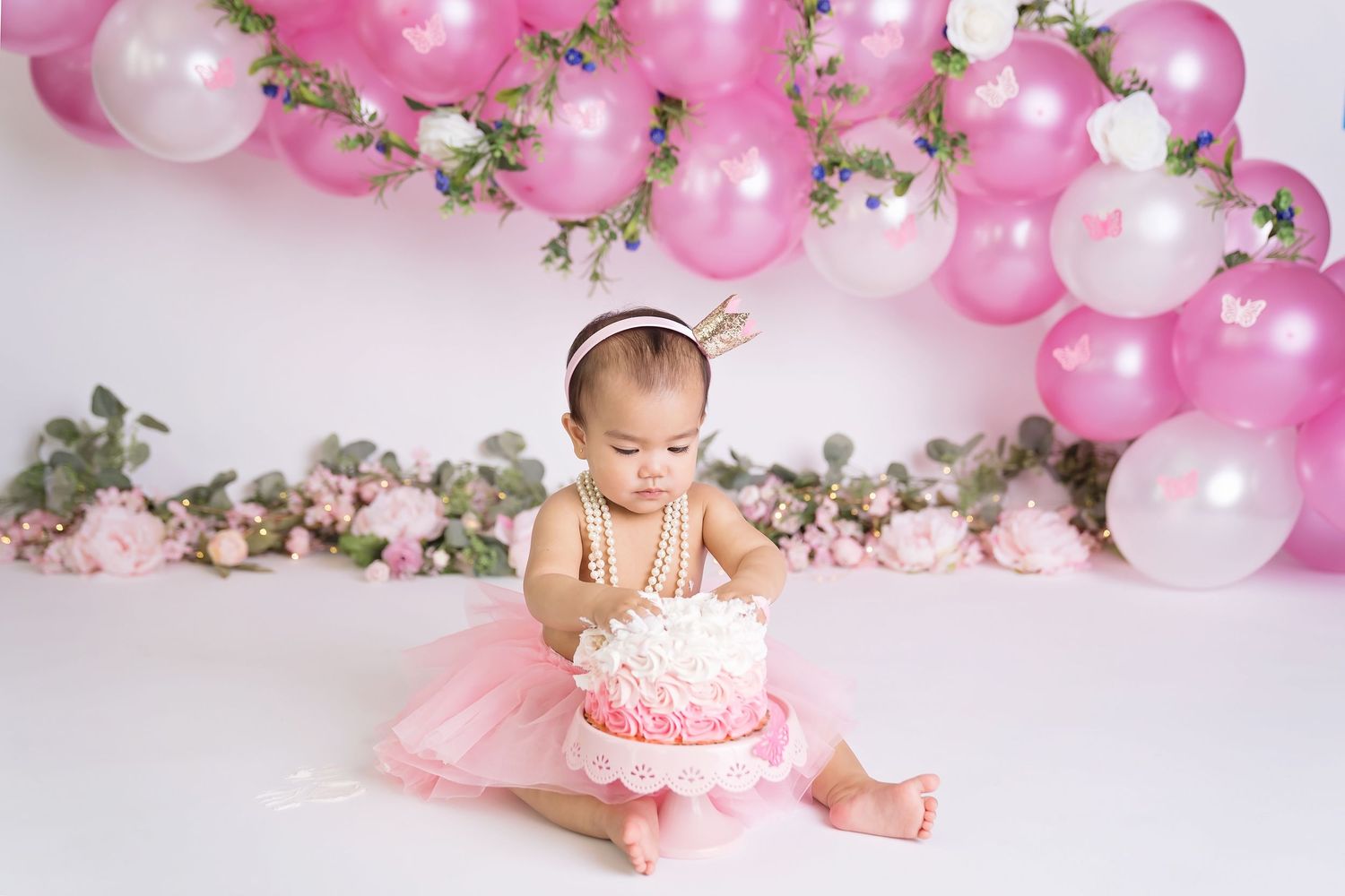Pink and white balloon arch with floral accents for baby photography session. San Diego cake smash photographer