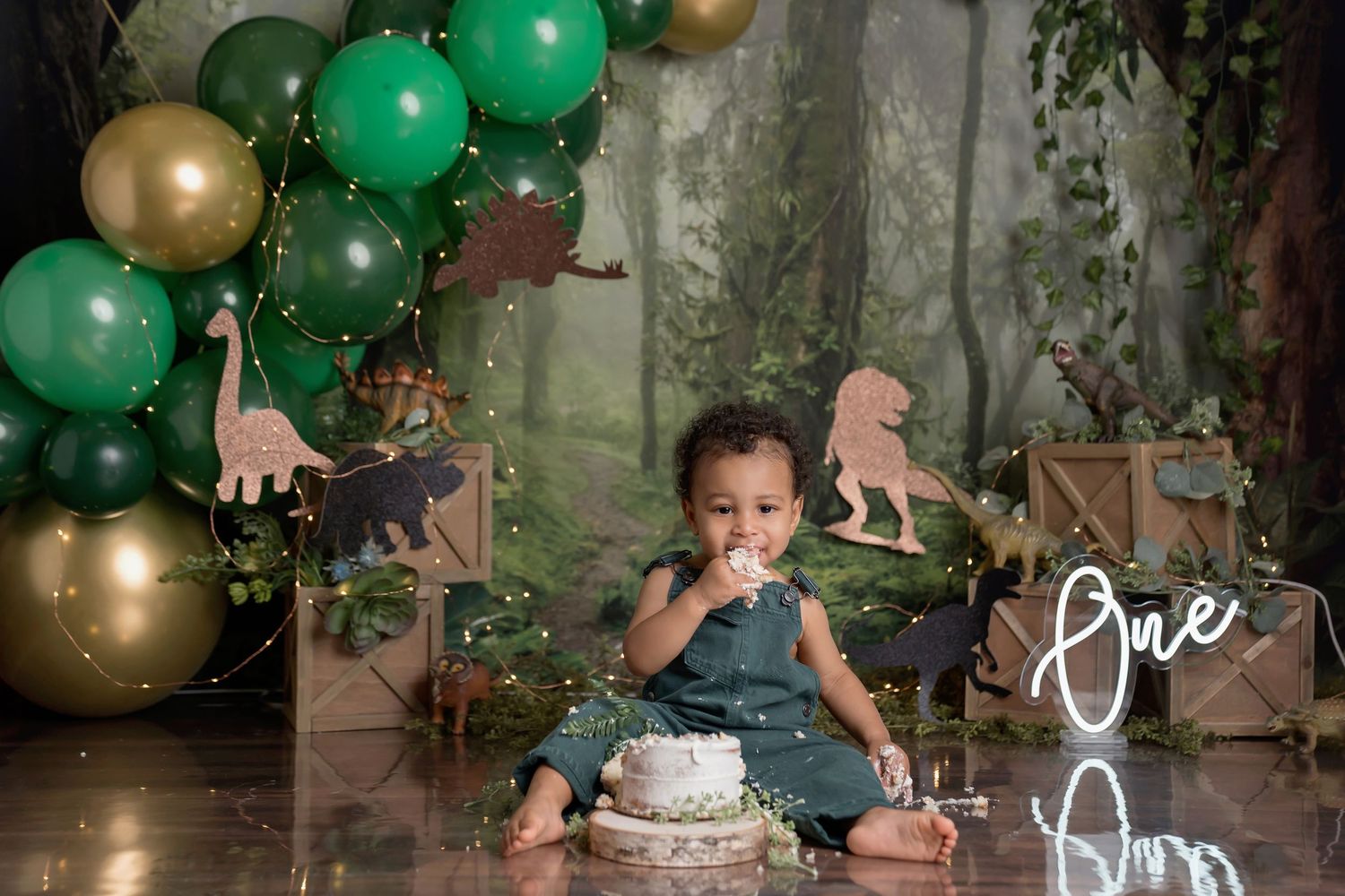 Woodland themed cake smash setup with green and gold balloons and rustic elements. Eastlake CA cake smash session