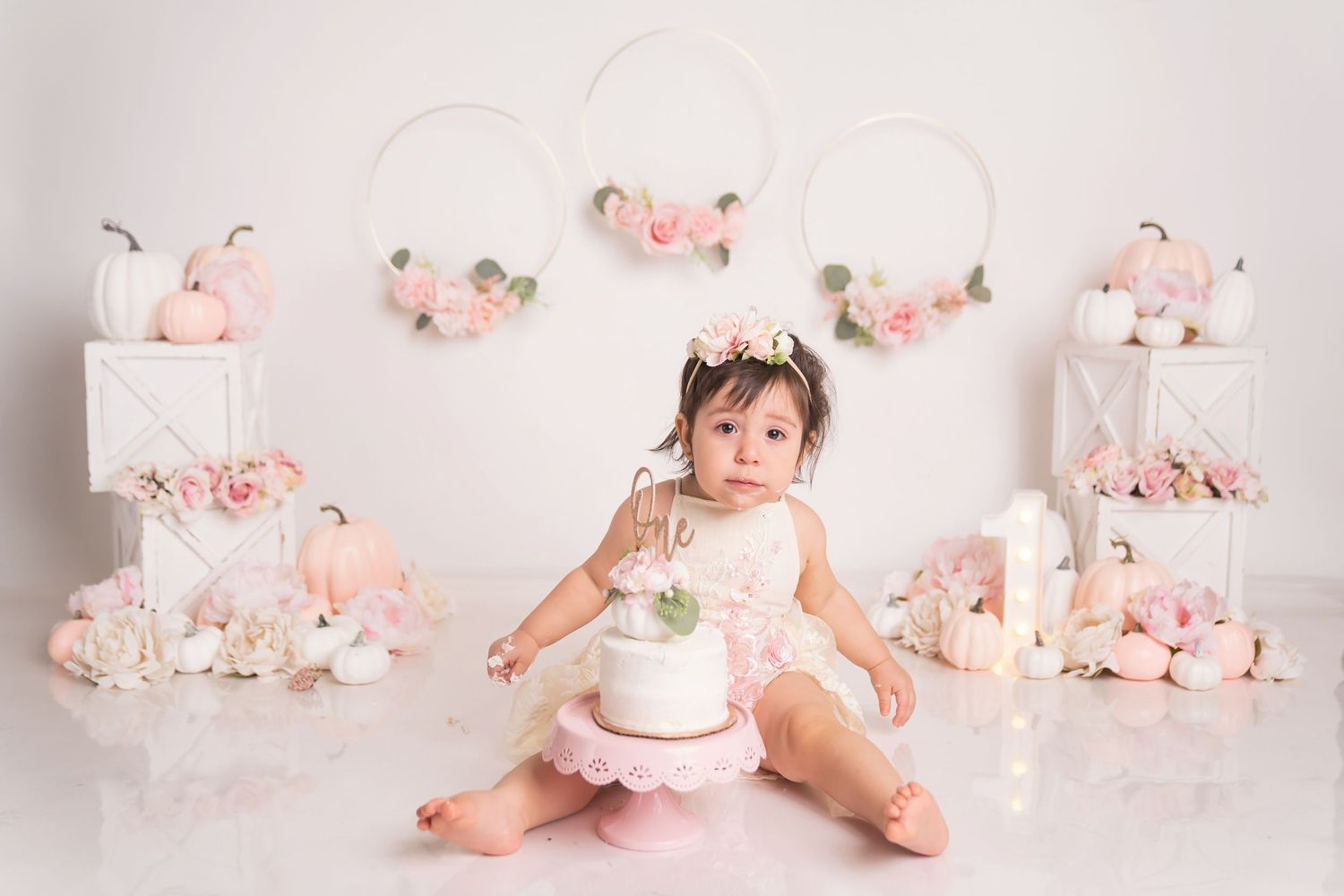 Delicate pink and white floral photography setup with vintage cake props.