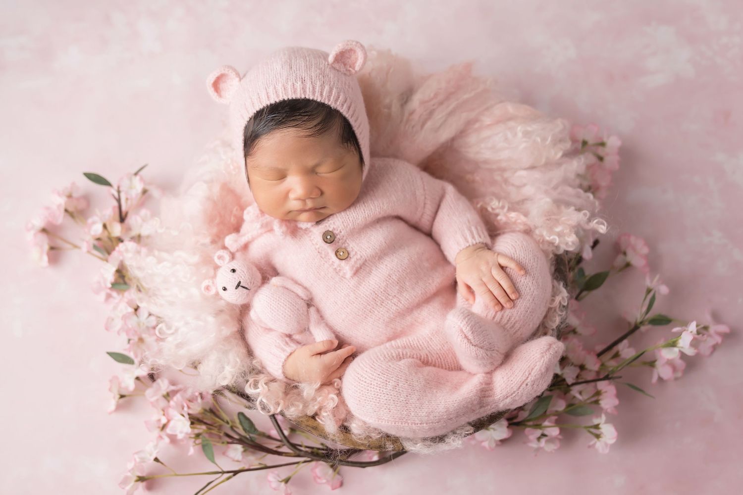Artistic newborn portrait series with pink cherry blossoms and soft textured backgrounds. San Diego Newborn Photographer