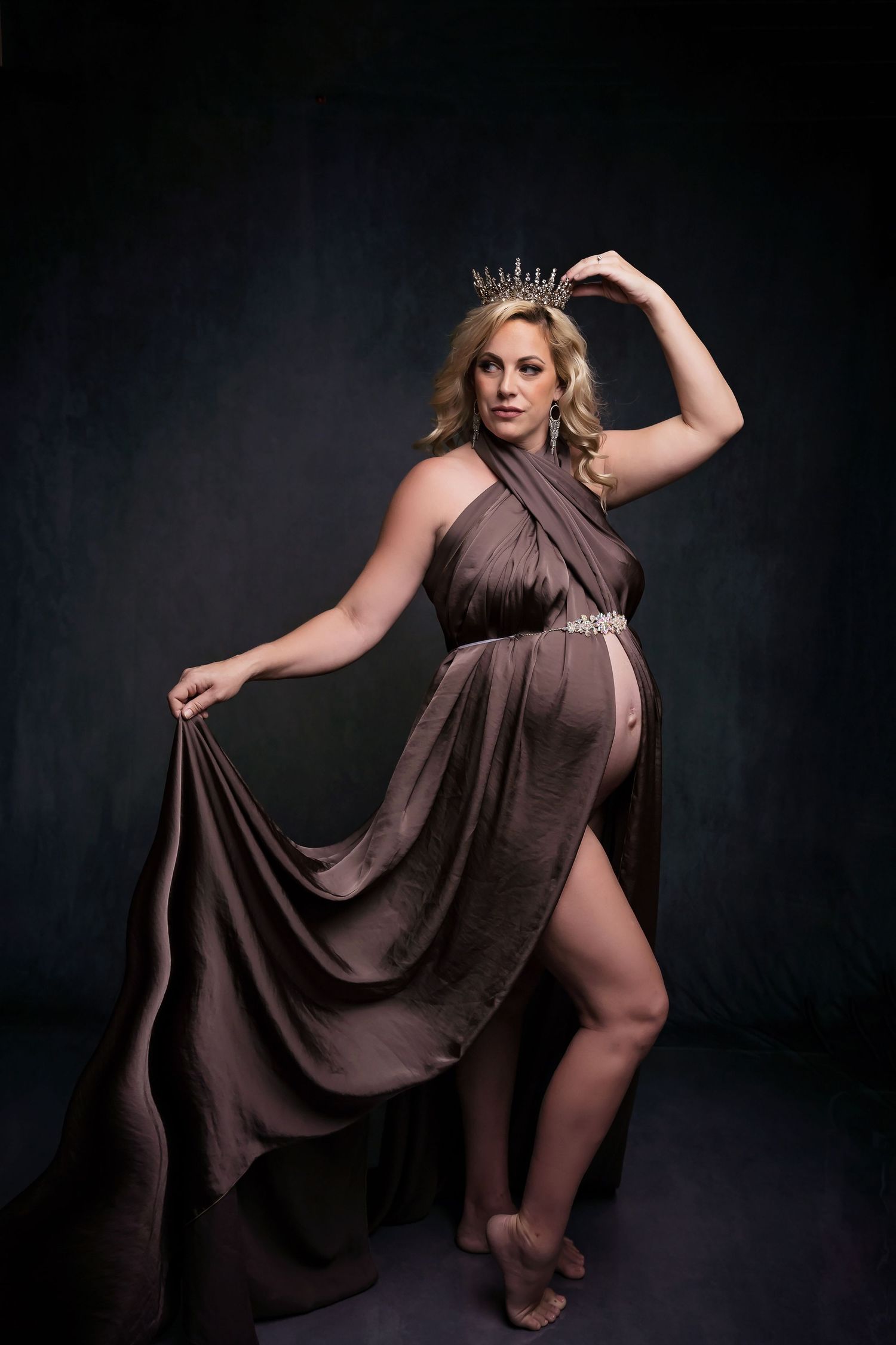 Maternity portrait featuring flowing mauve dress and dramatic posing