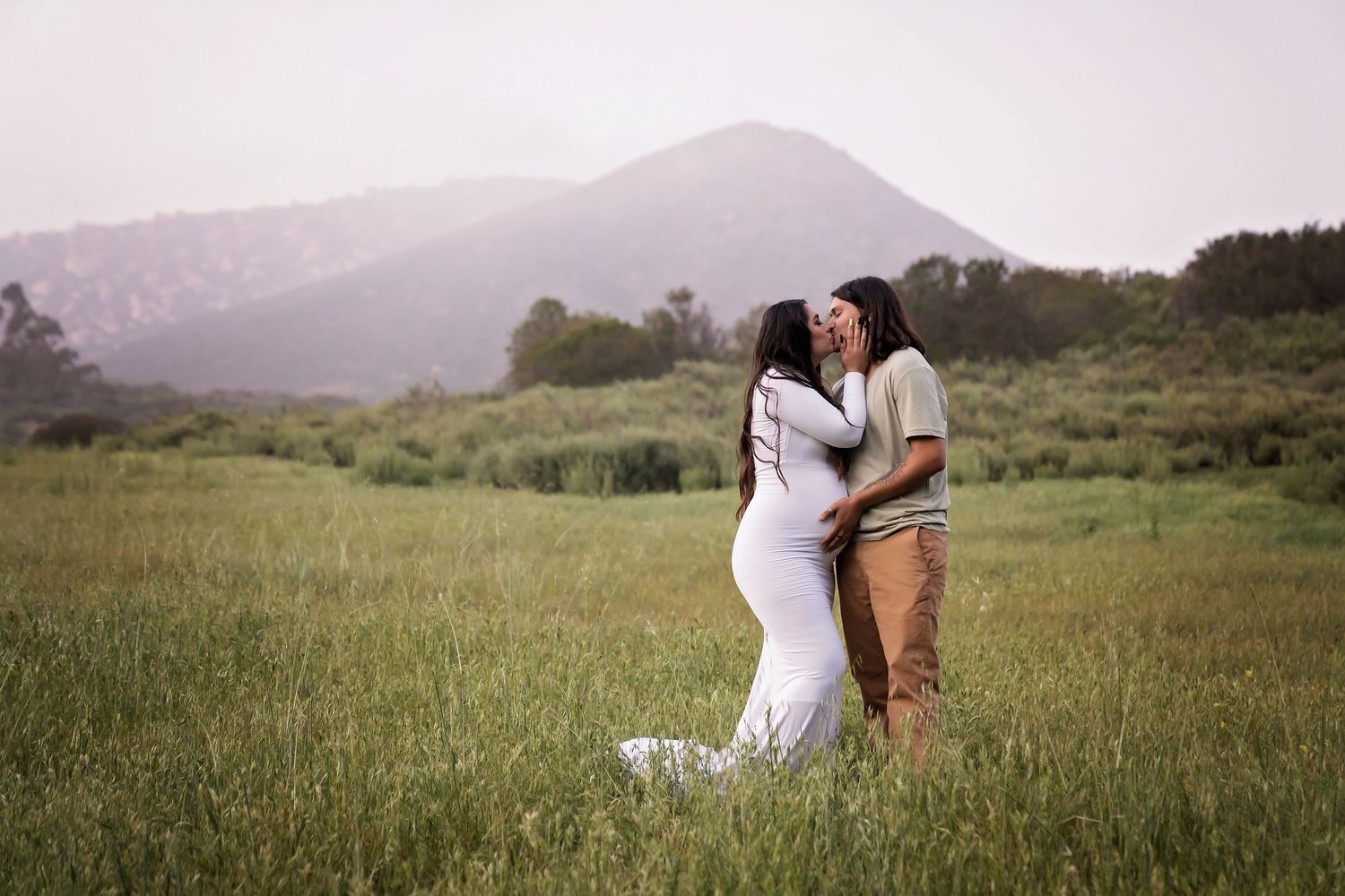 Maternity photography in a grassy field with mountains in the background. San Diego Maternity Photographer