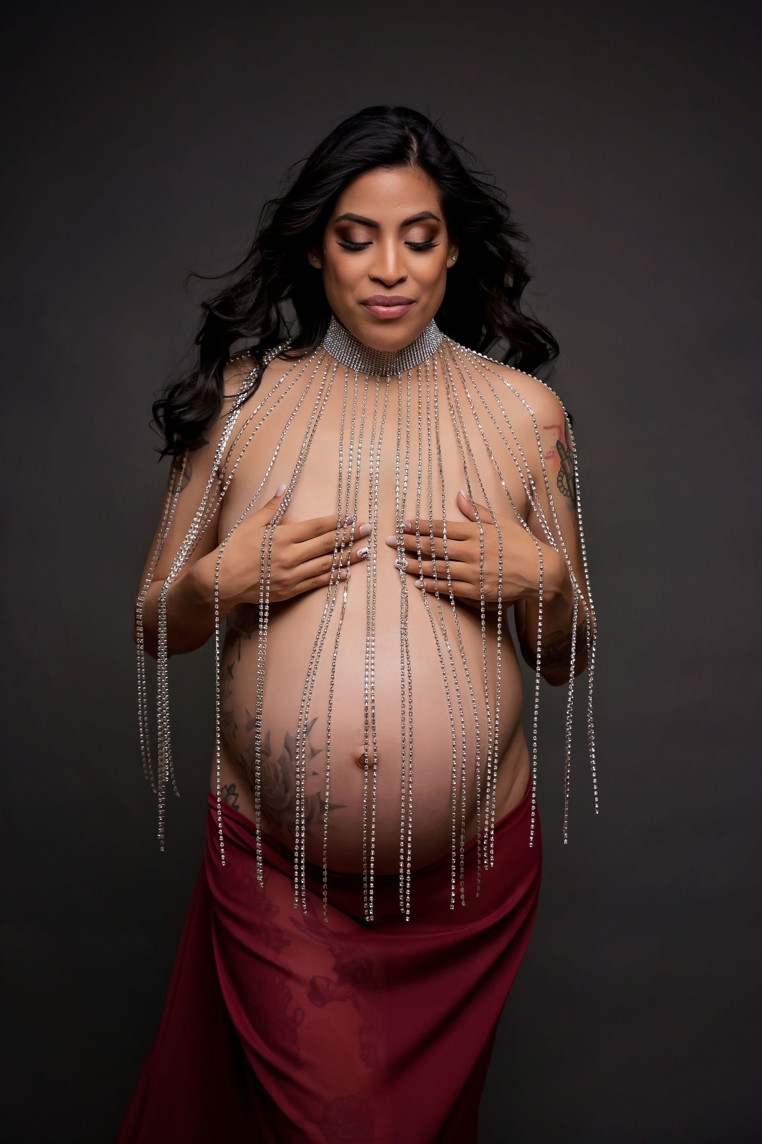 Dramatic maternity portrait with rhinestone strands and burgundy fabric