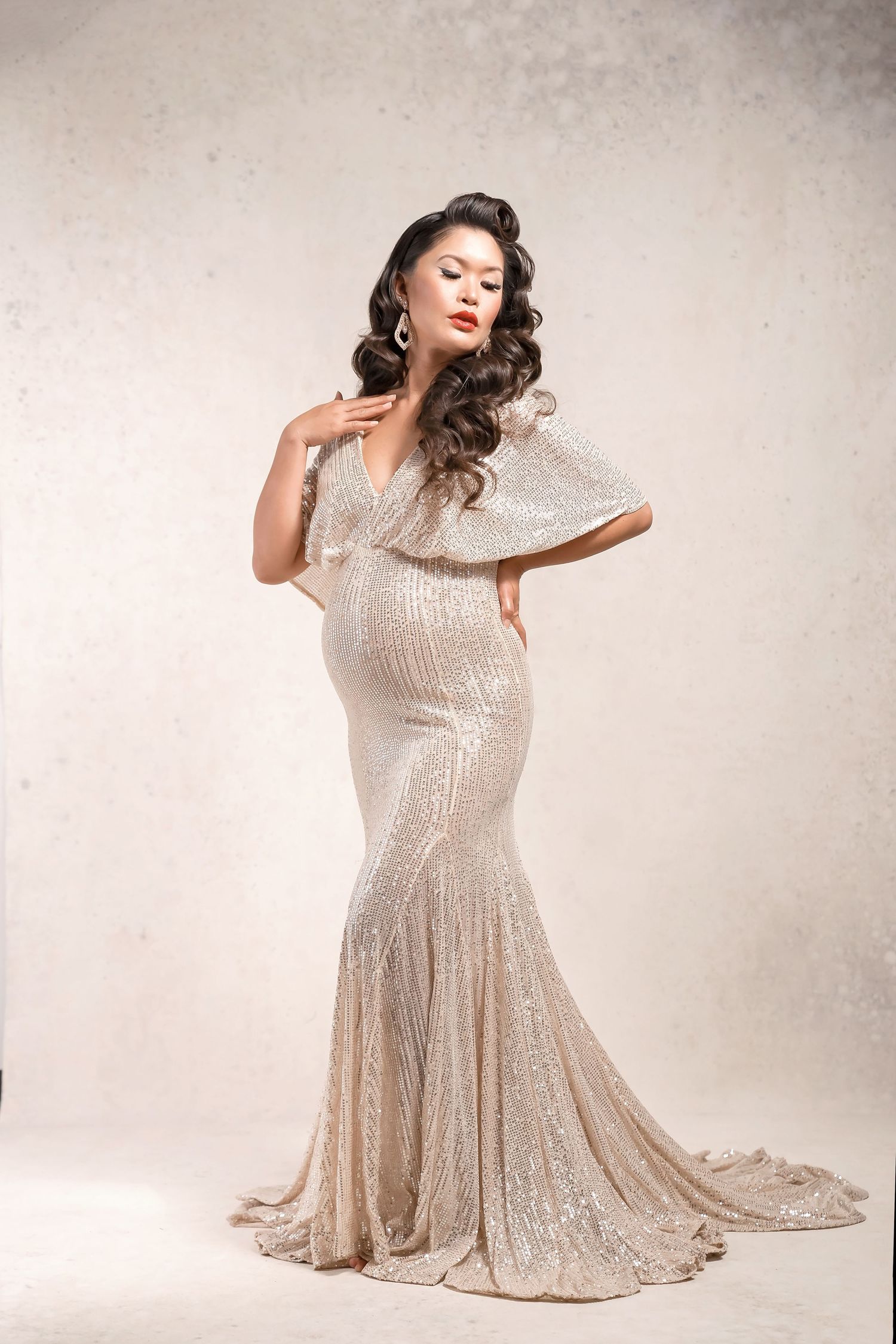Glamorous maternity poses in sparkling ivory gown with dramatic lighting. Vintage Maternity Pose in San Diego Photography studio