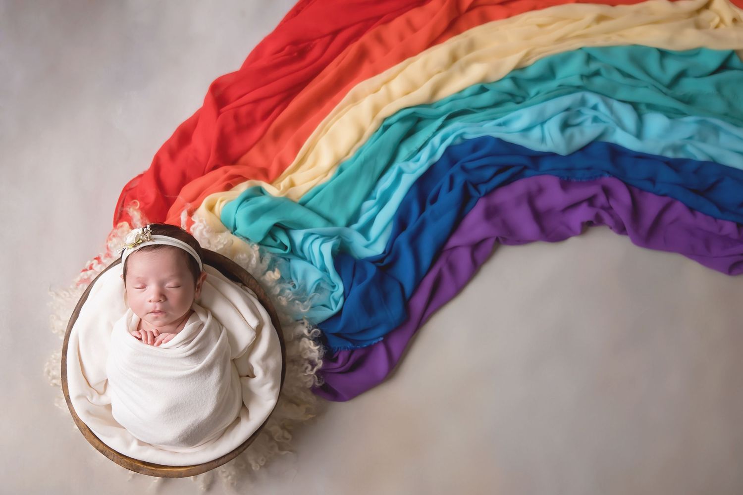 Rainbow fabric backdrop creates colorful setting for newborn portrait session. San Diego Newborn Photographer