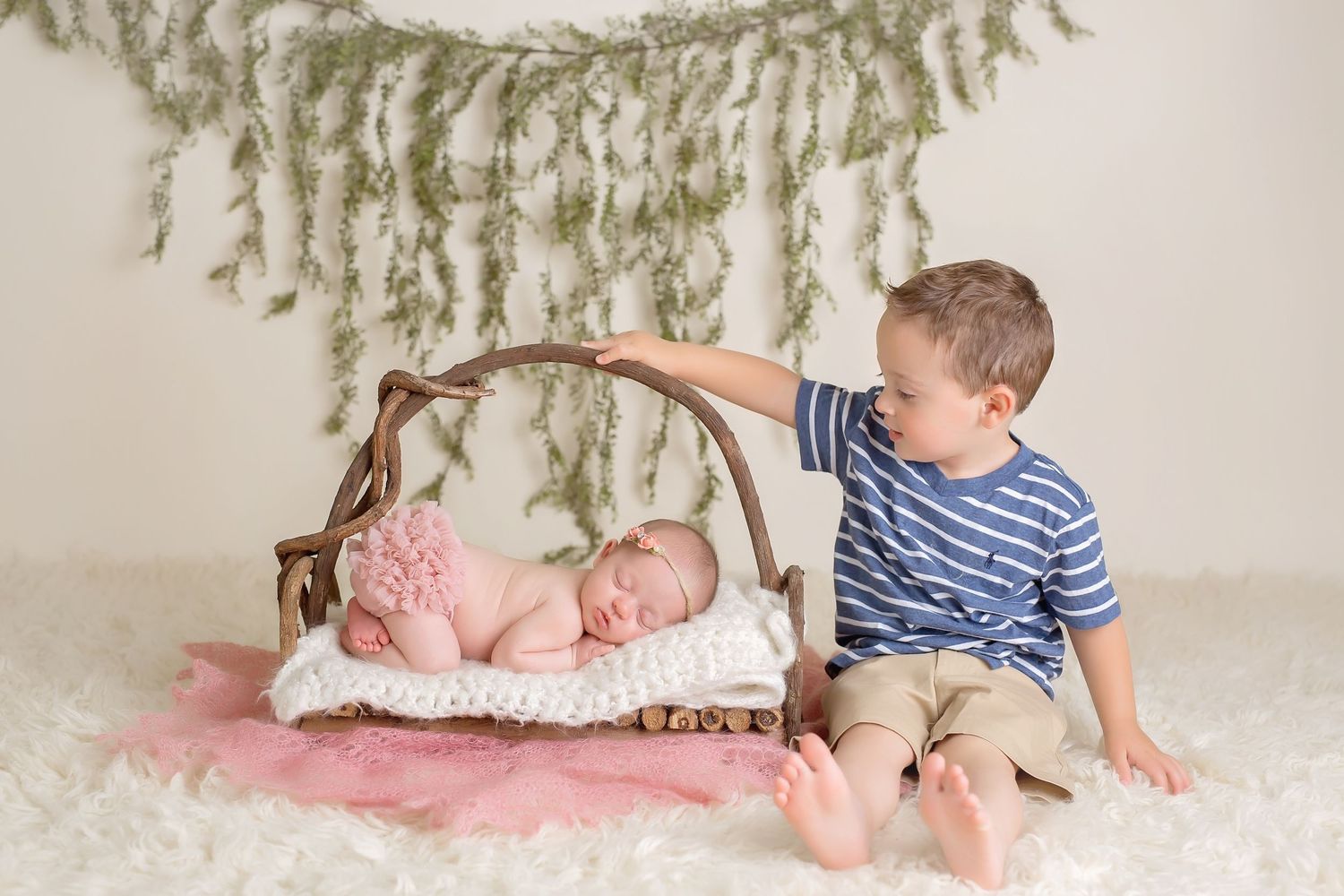 Baby photography session with rustic branch decorations and pink floral accents. San Diego Newborn Photographer