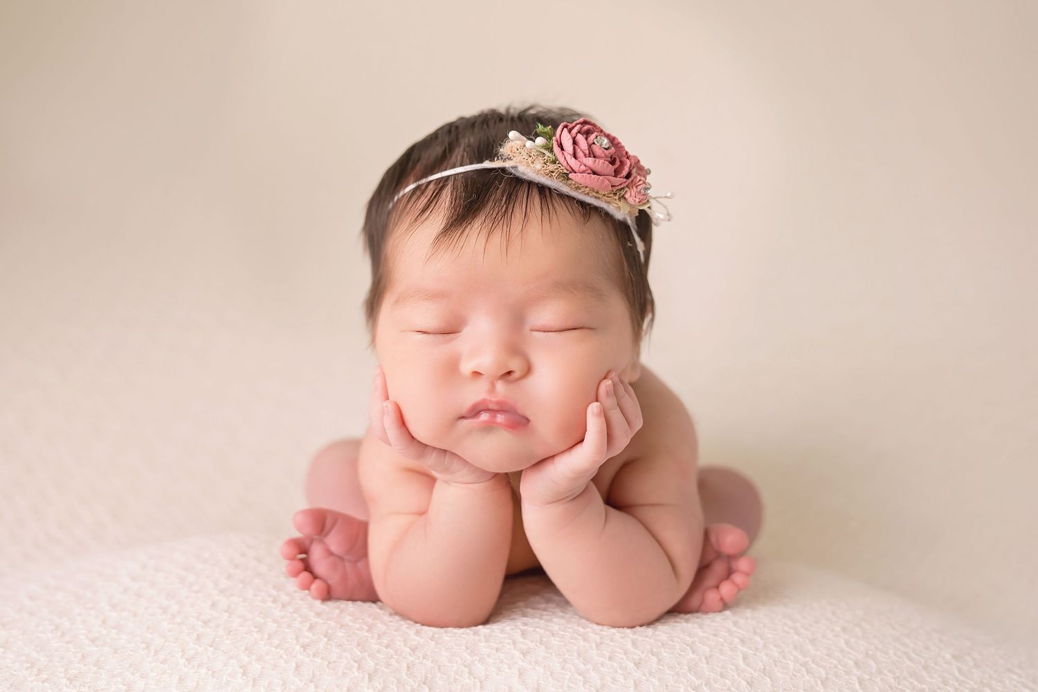 Newborn baby sleeping peacefully in soft pink tones during professional photo session in san diego newborn photography studio