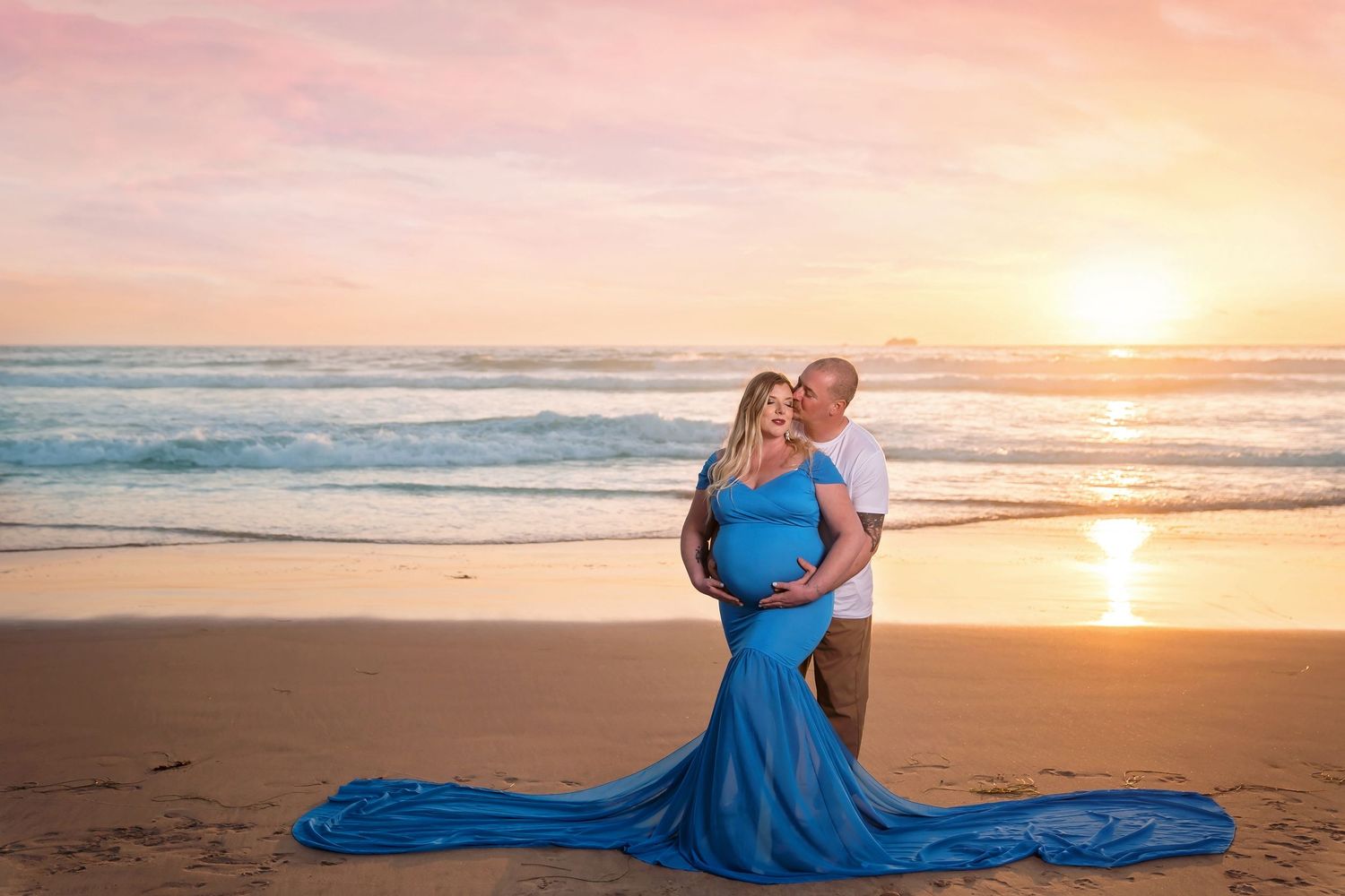 A flowing blue dress catches the ocean breeze during a golden beach sunset. San Diego Maternity Photographer