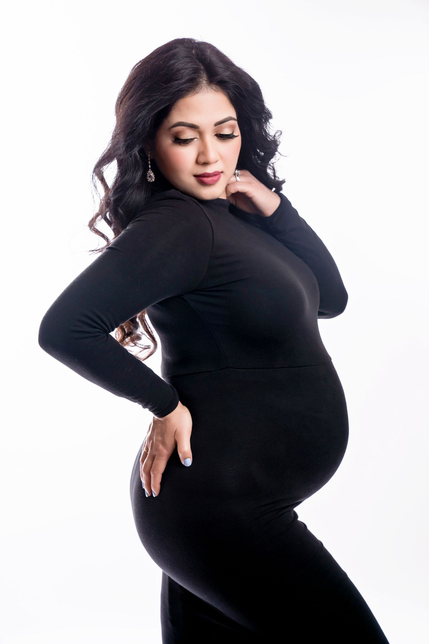 Minimalist maternity studio portrait in black outfit against white backdrop