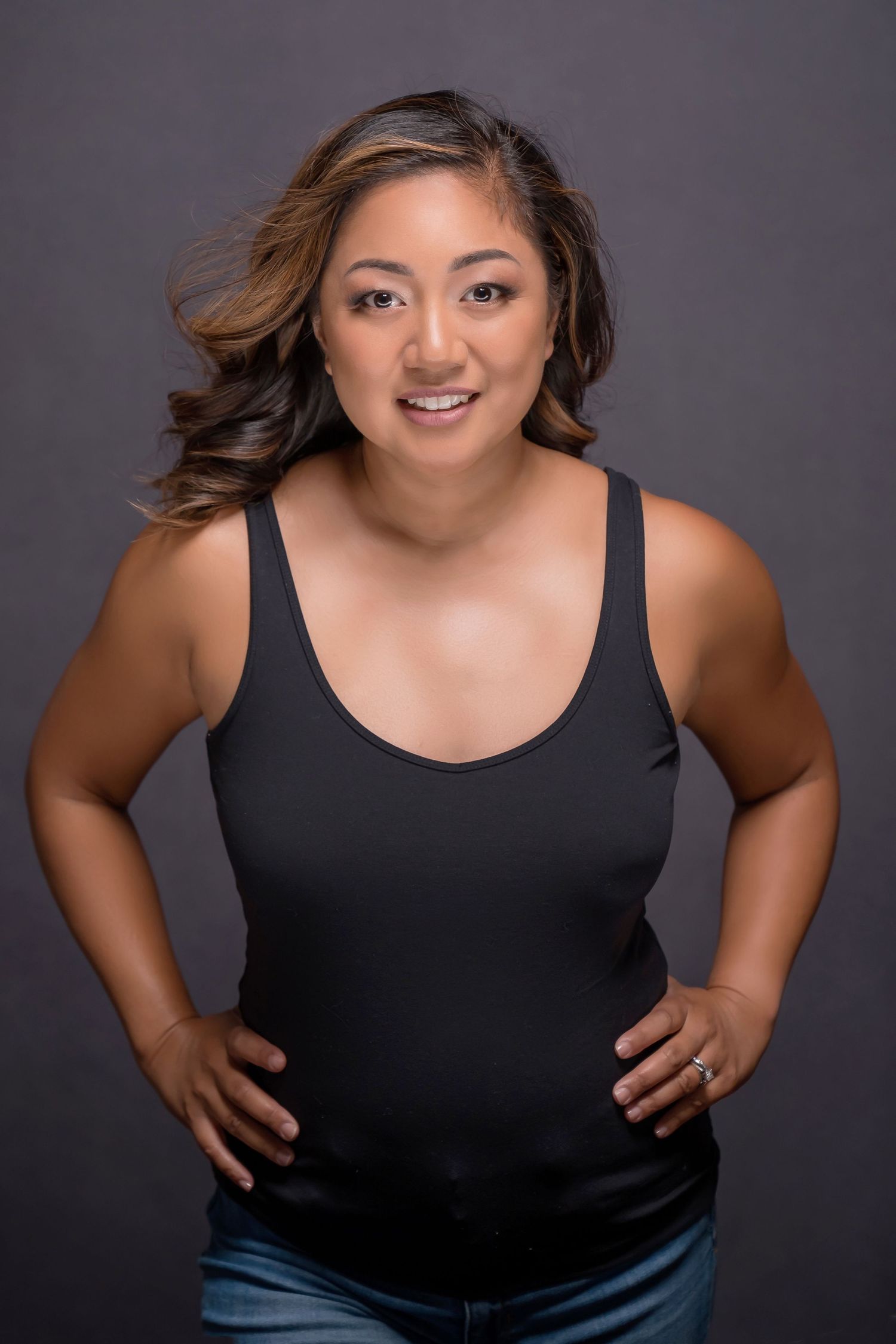 Portrait series of woman in black tank top posed casually against dark background