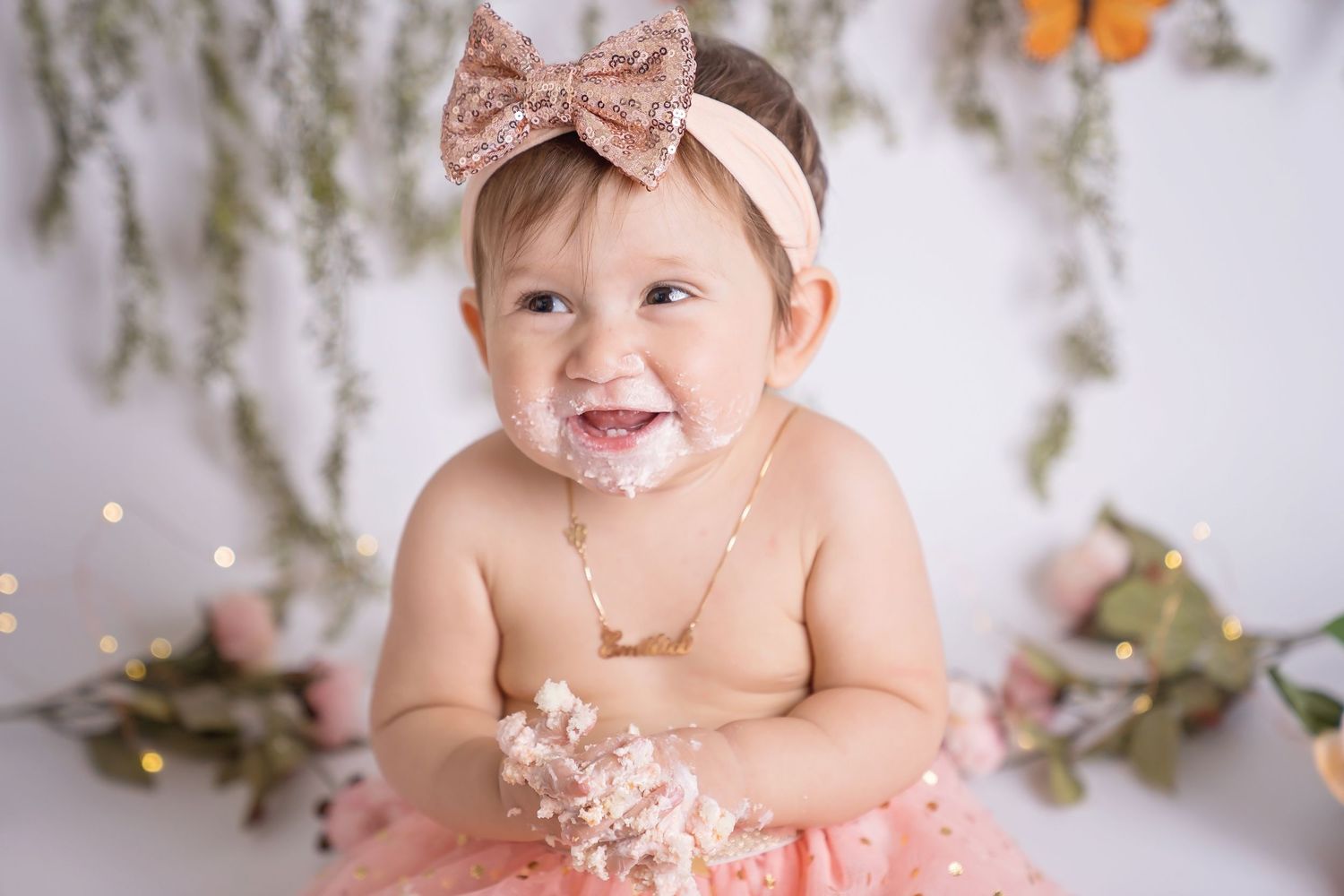 Ethereal white studio setup with hanging florals and butterflies for baby portraits. San Diego cake smash photographer