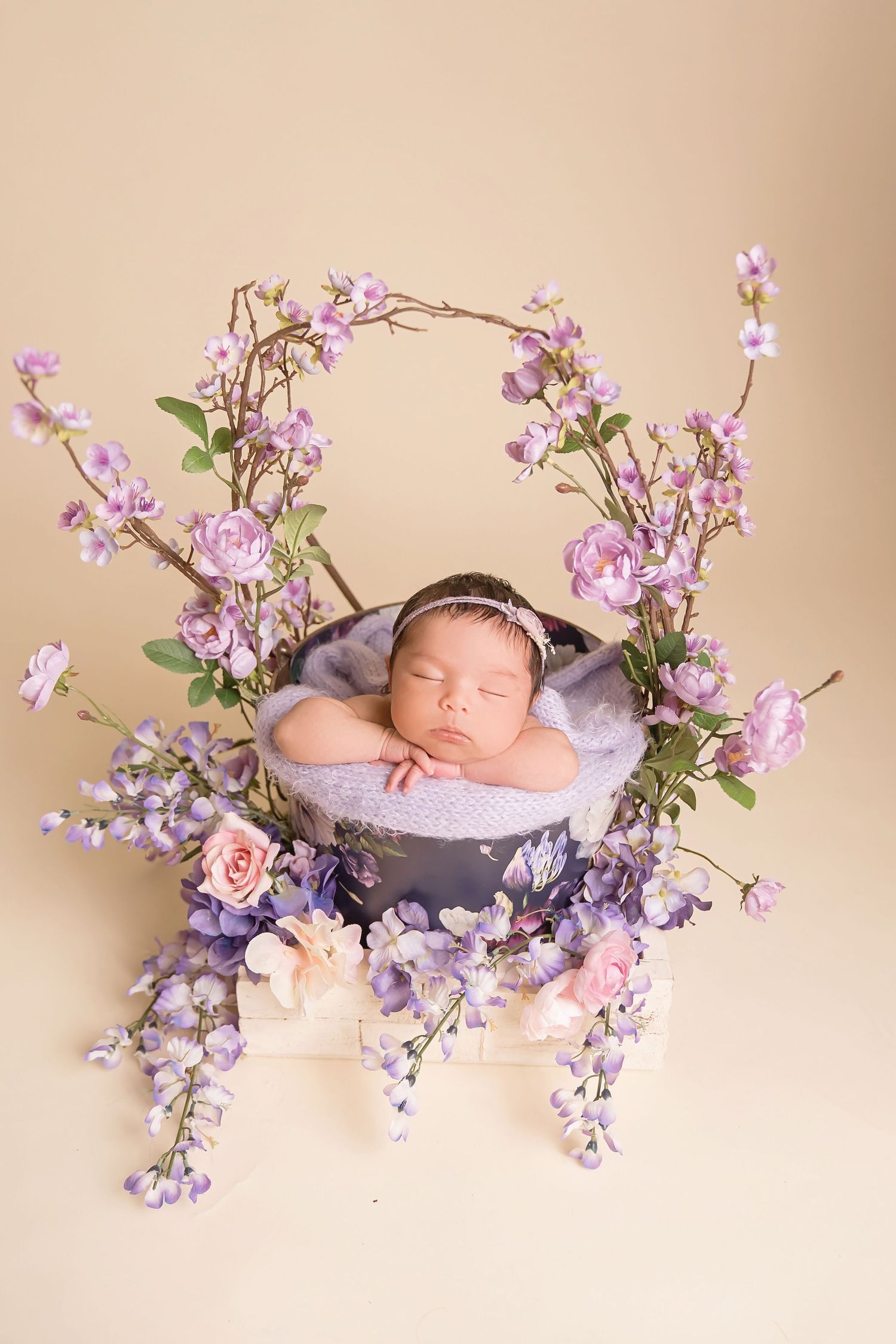San Diego newborn photographer captures Newborn photography setup with purple wisteria flowers and soft pink basket.
