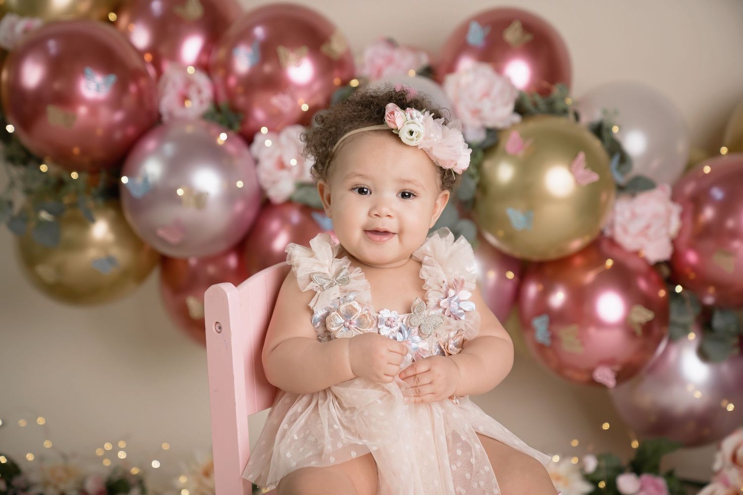 Elegant rose gold and pink balloon garland with floral accents for birthday photography. San Diego cake smash photographer