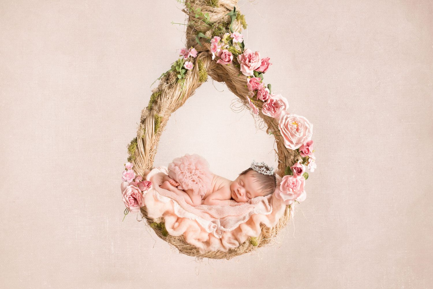 Sleeping newborn in pink floral wreath swing with delicate rose decorations. San Diego Newborn Photographer