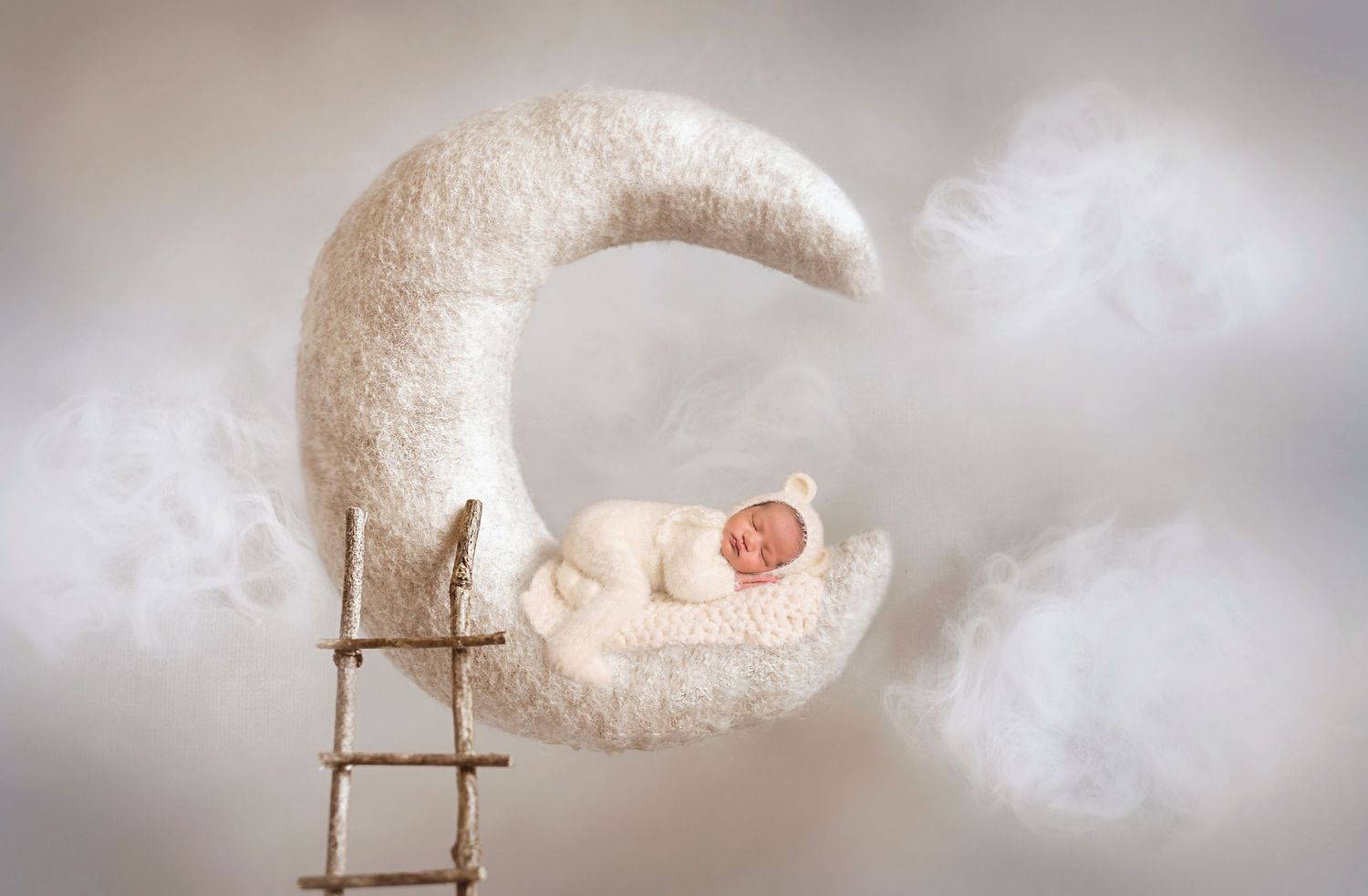 San Diego newborn photographer captures Newborn sleeping peacefully on a dreamy crescent moon prop with soft clouds in the background.