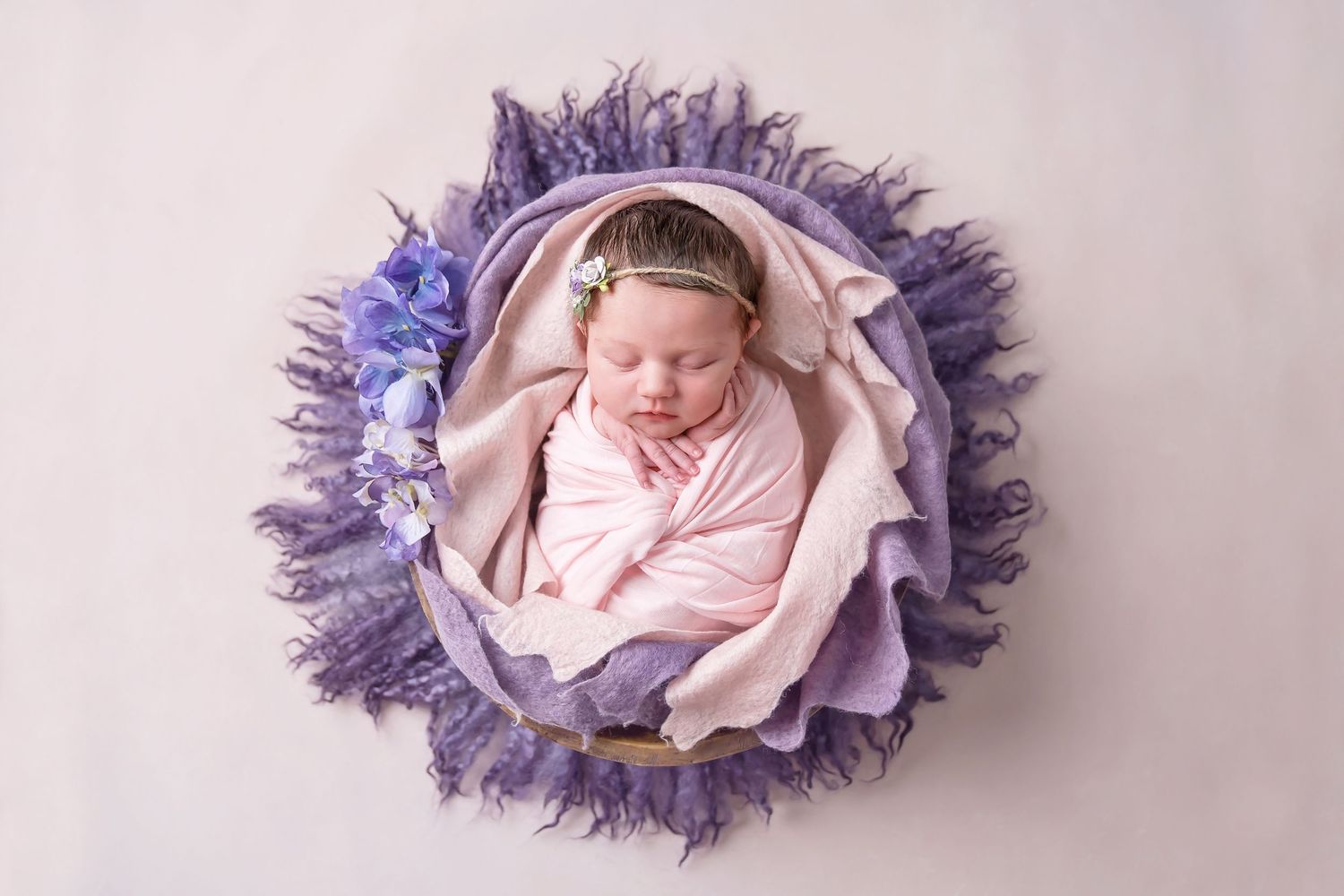 Artistic newborn photo with purple tulle fabric creating a nest-like setting. San Diego Newborn Photographer