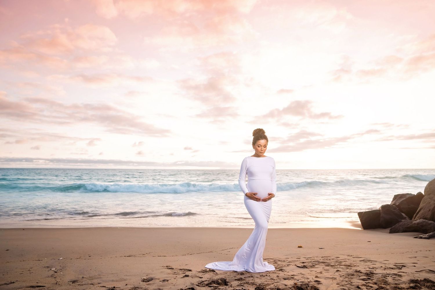 Ethereal beach portraits with flowing white dress against pink sunset sky. San Diego Maternity Photographer