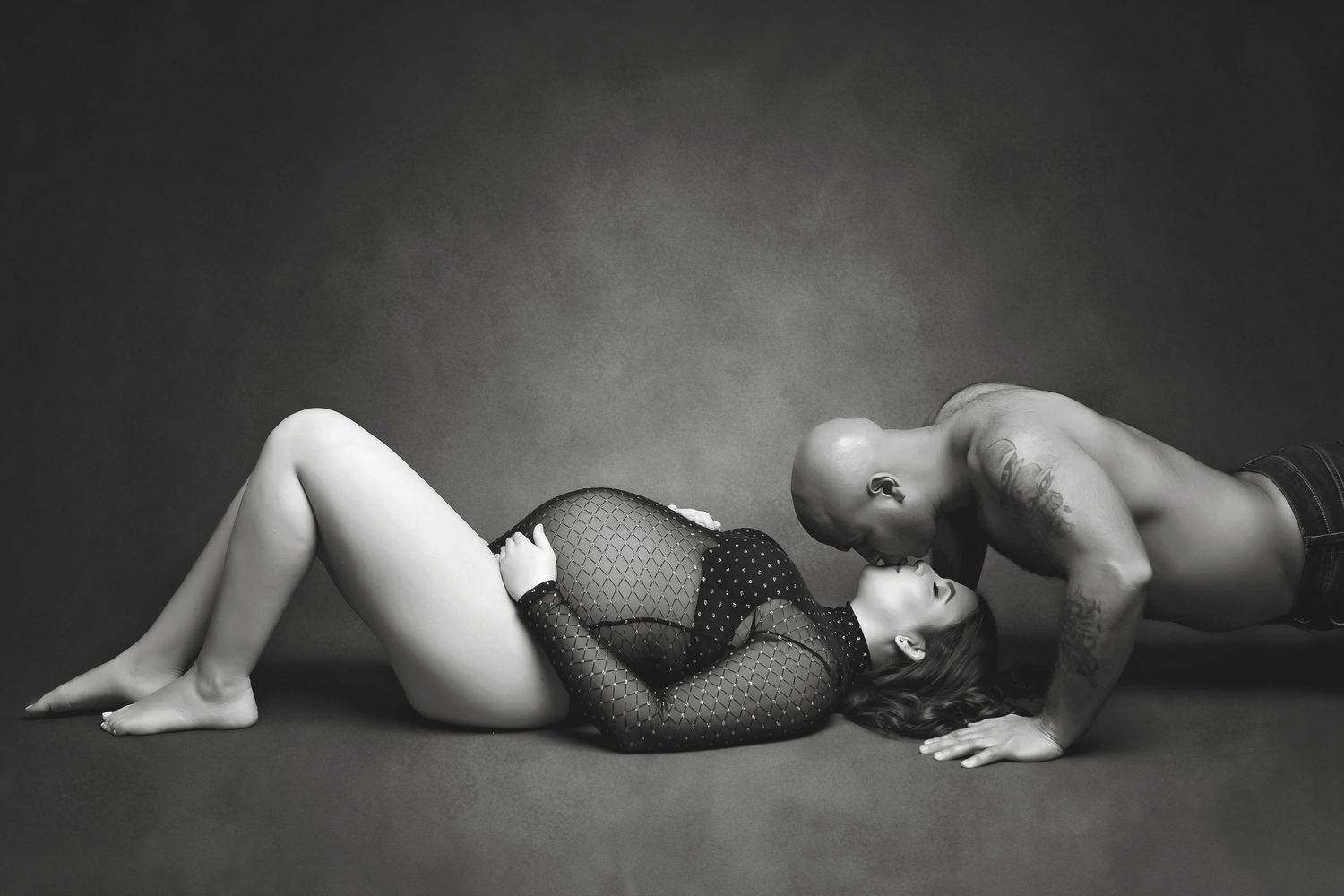 Black and white intimate maternity silhouette of two figures against dark background