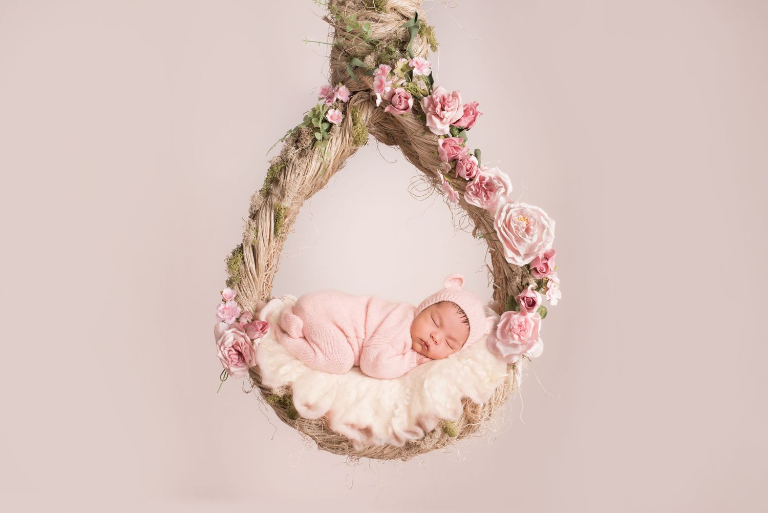 San Diego newborn photographer captures sleeping newborn baby in a hanging wrath against a blush background.