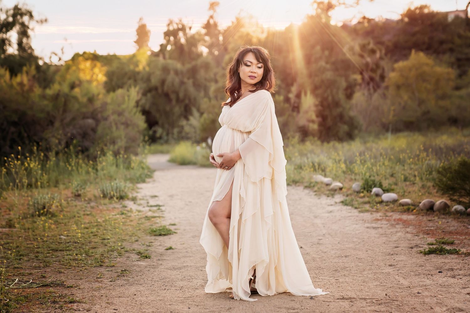 Golden hour maternity session on dirt path with flowing white dress. San Diego Maternity Photographer