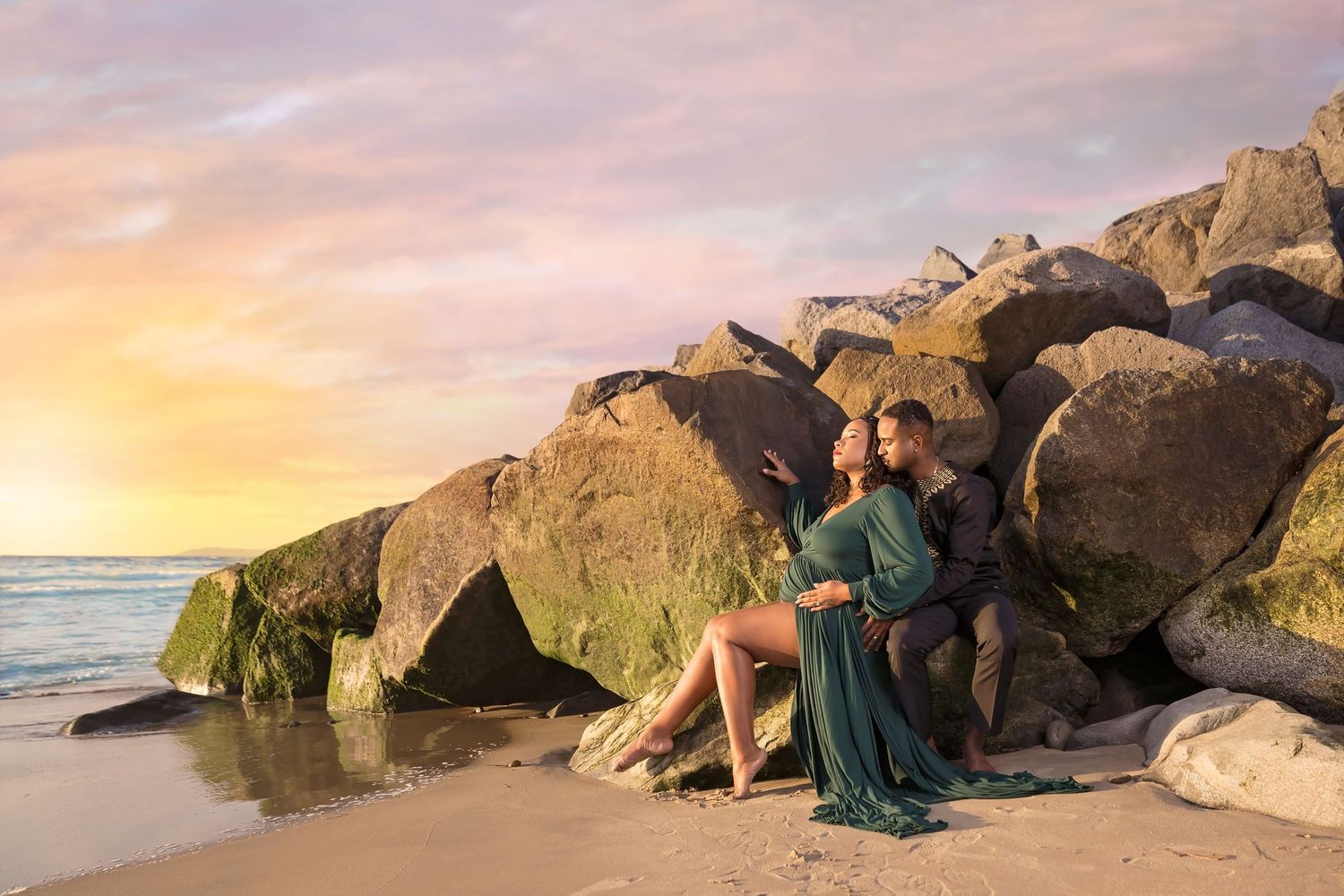 Dramatic coastal portraits with subjects posed among large mossy rocks at golden hour. San Diego Maternity Photographer