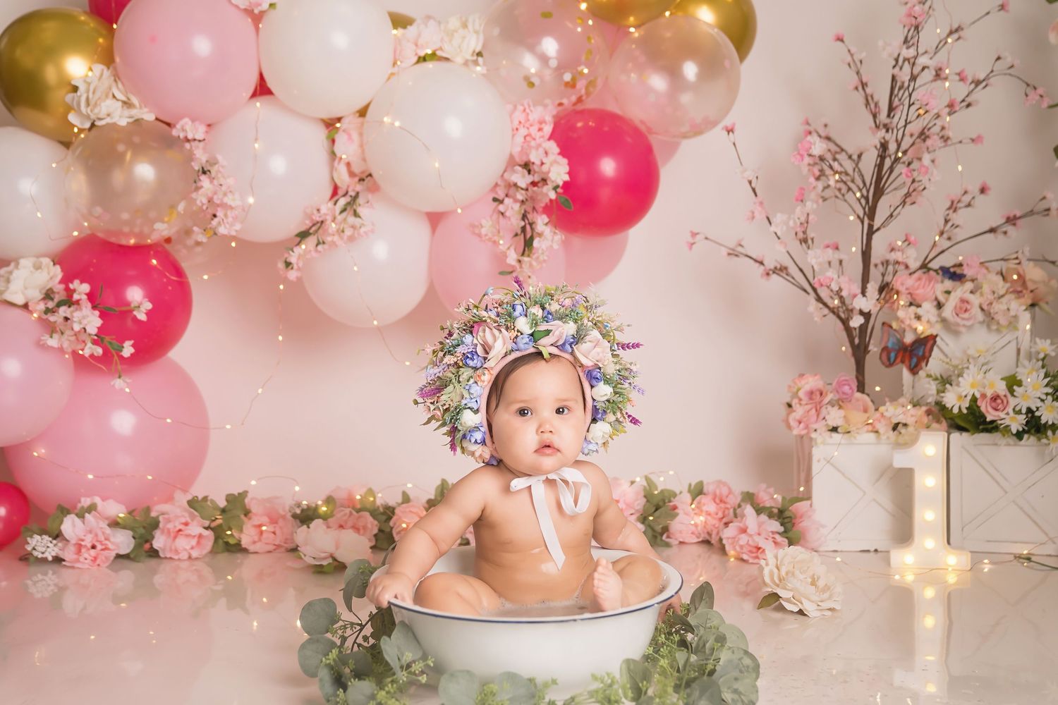 Whimsical floral setup with pink balloons and cherry blossoms against cream backdrop.