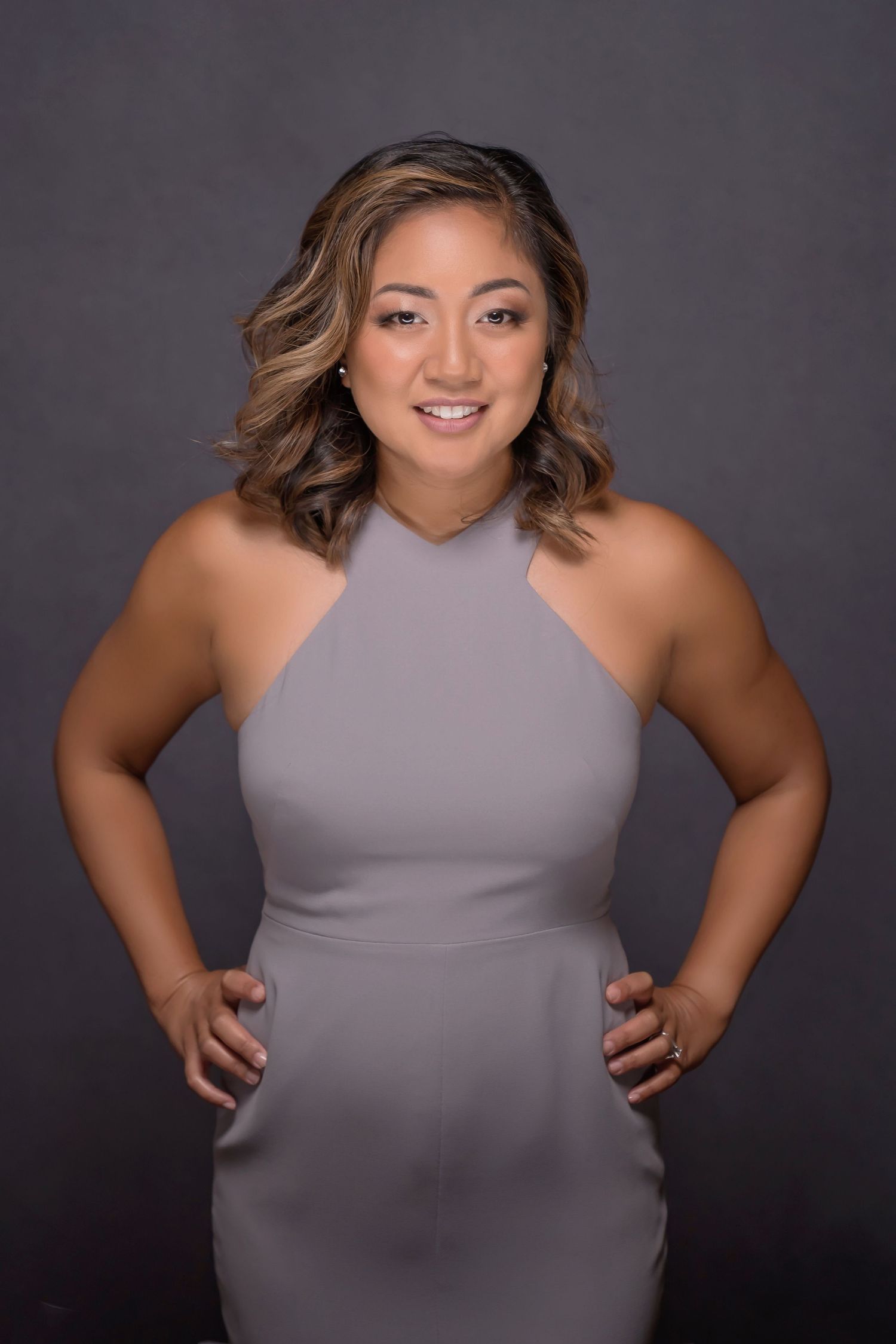 Portrait of woman in gray halter dress against dramatic dark studio background