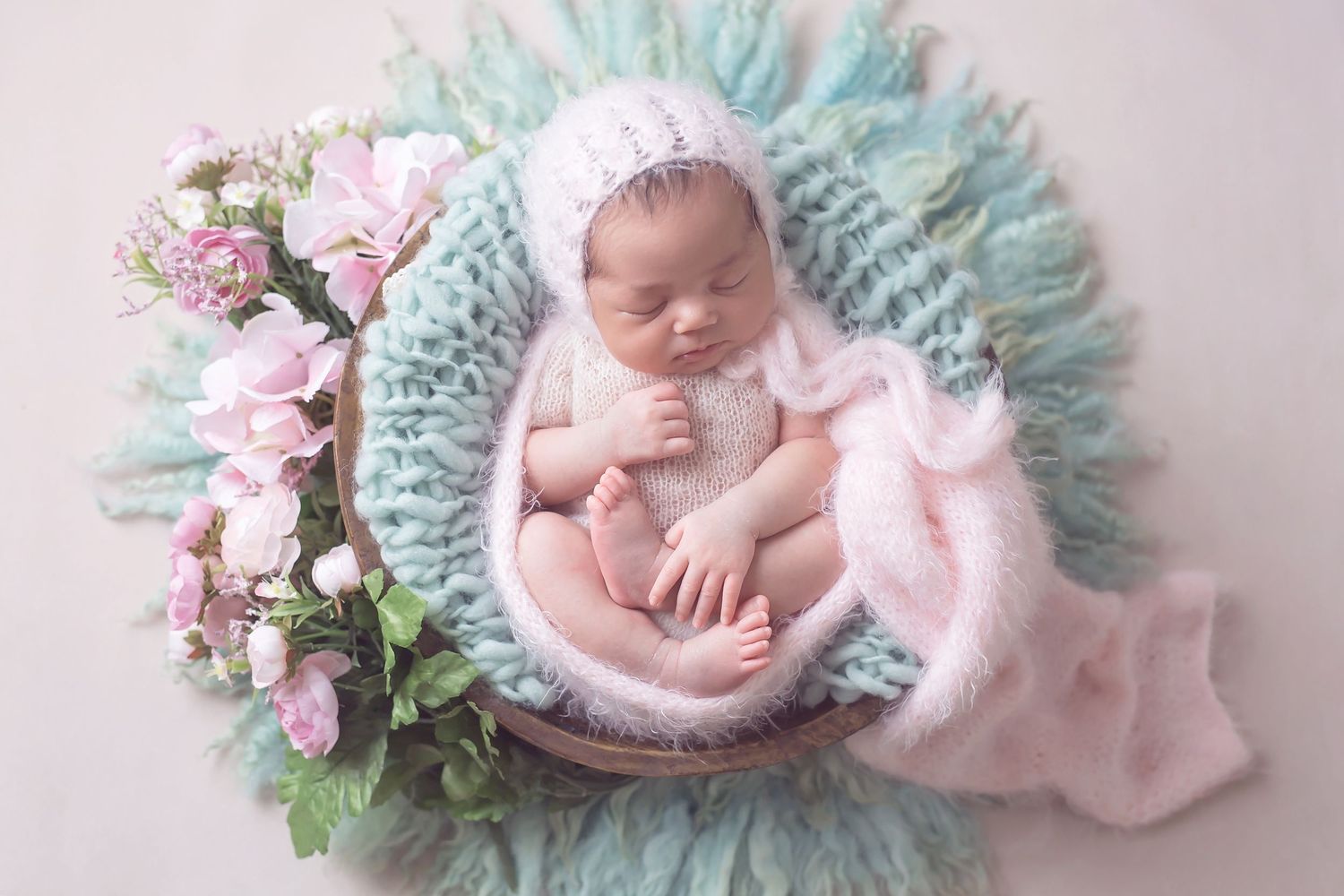 San Diego newborn photographer captures Whimsical newborn portrait with mint soft fabric and pink floral accents.