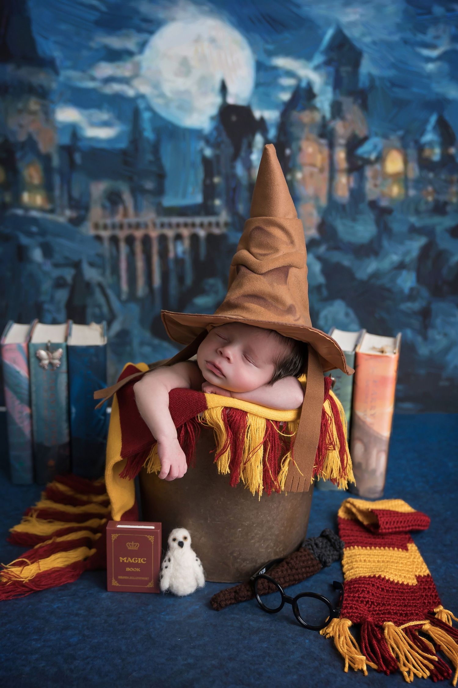 Magical newborn portrait with Hogwarts castle backdrop and wizard accessories. San Diego Newborn Photographer