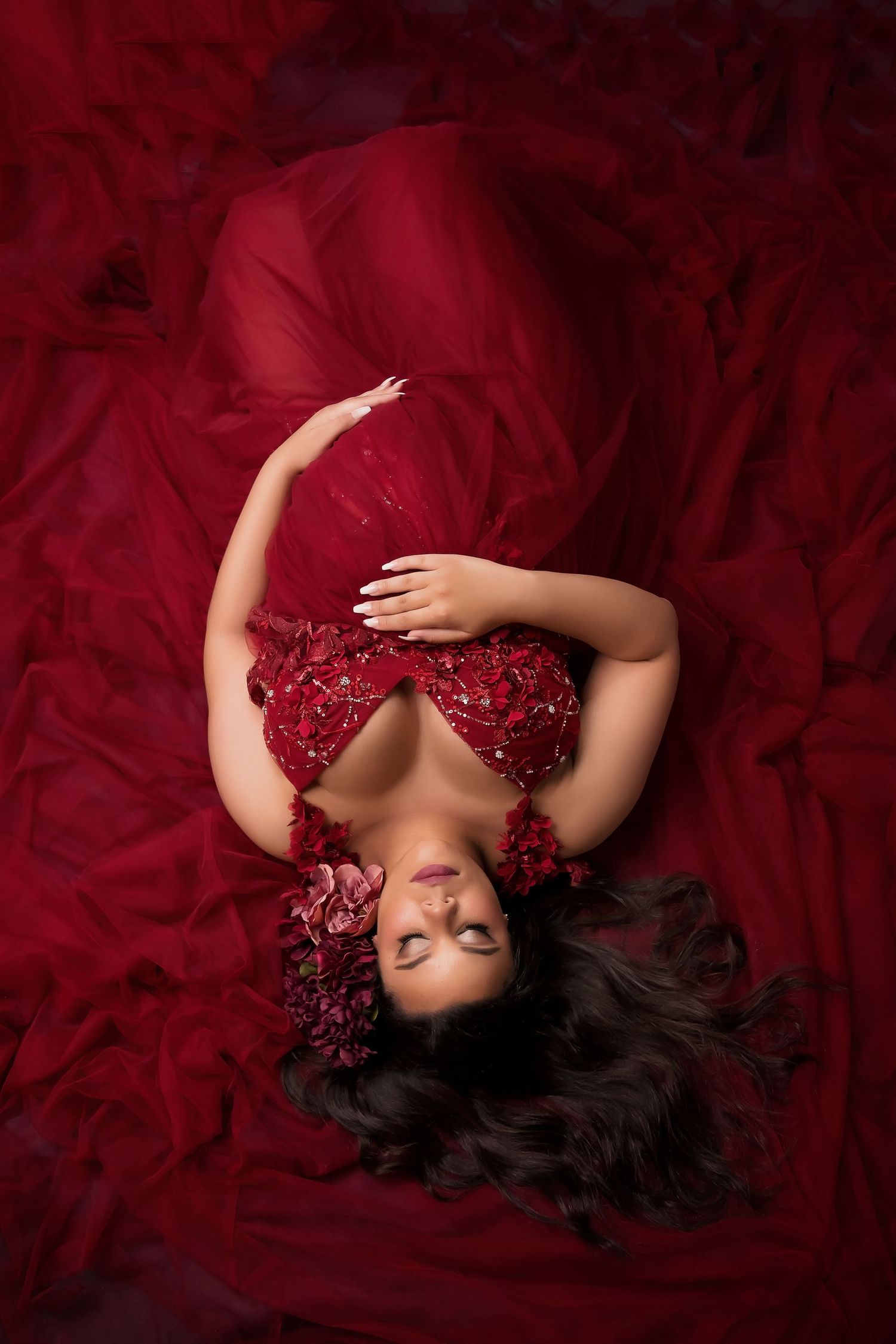 San Diego Maternity Photographer captures A dramatic maternity photo with a flowing red sequined gown against deep burgundy fabric backdrop.