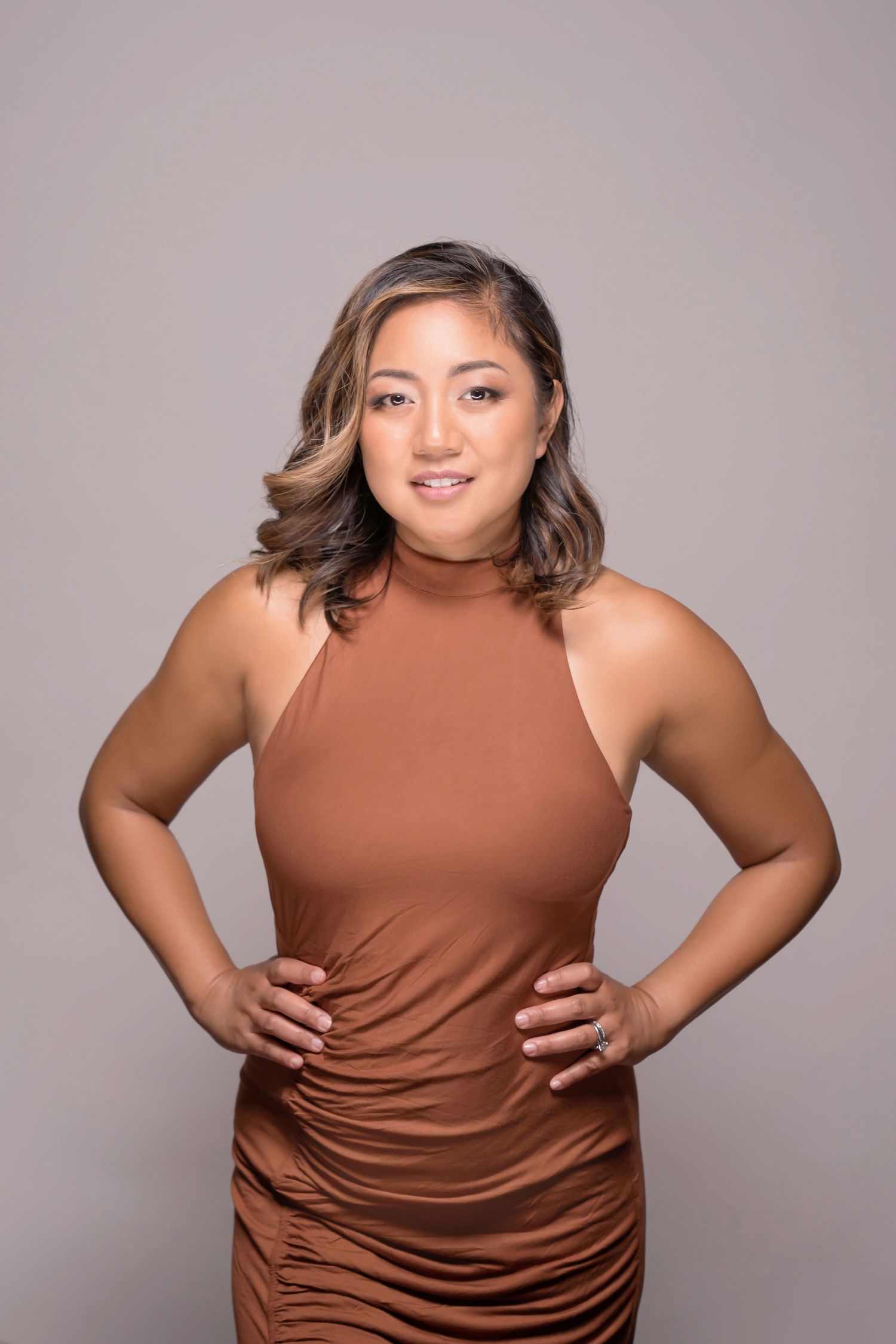 Studio headshot featuring woman in brown fitted top with expressive posing