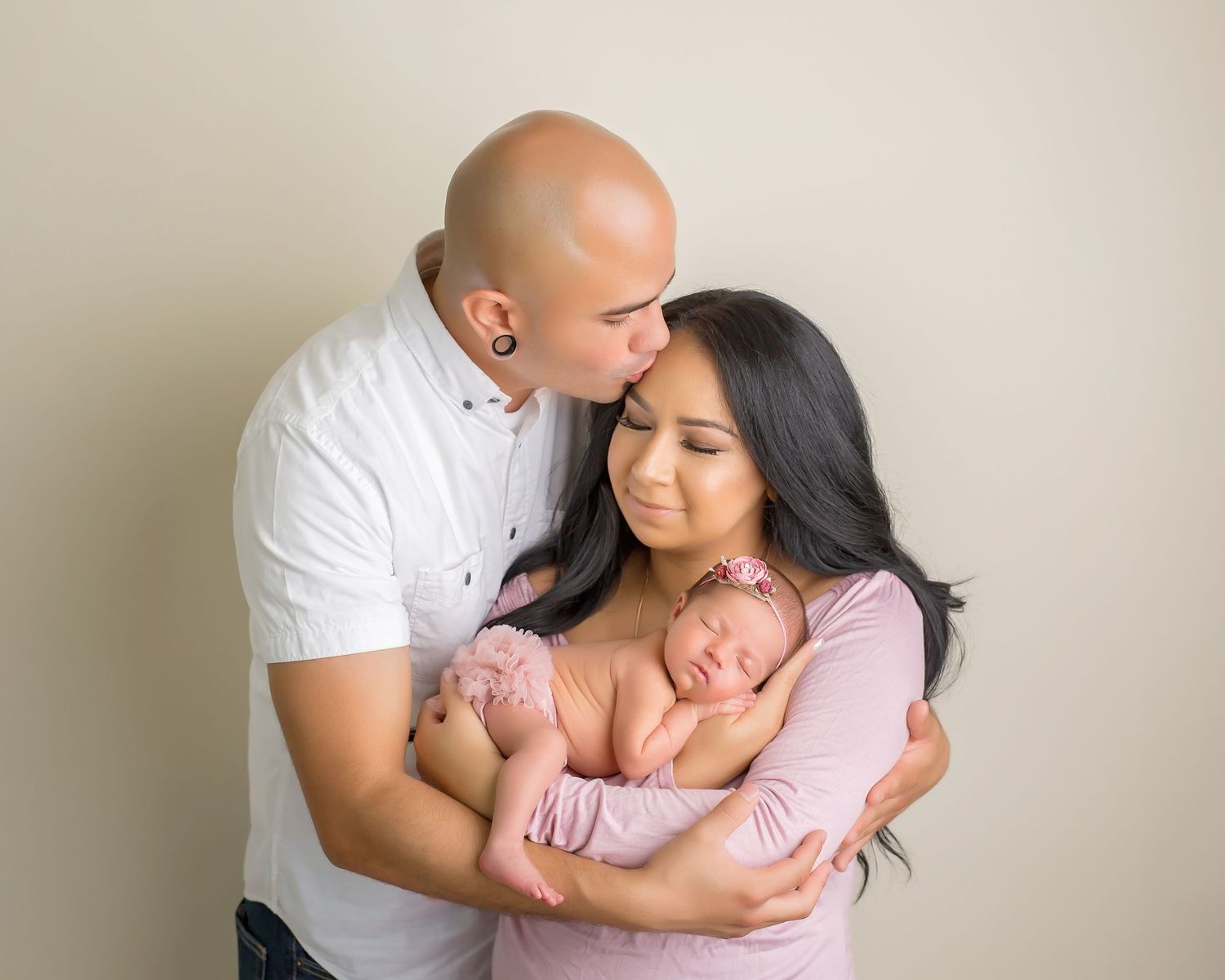 Family embracing during intimate portrait session against neutral background. San Diego Newborn Photographer