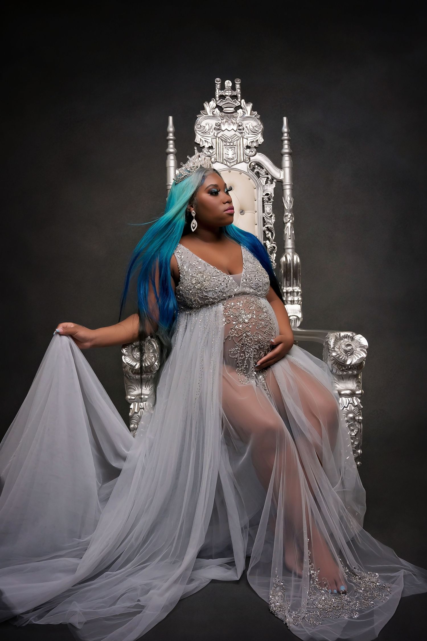 Regal maternity portrait with ornate silver throne and embellished silver gown