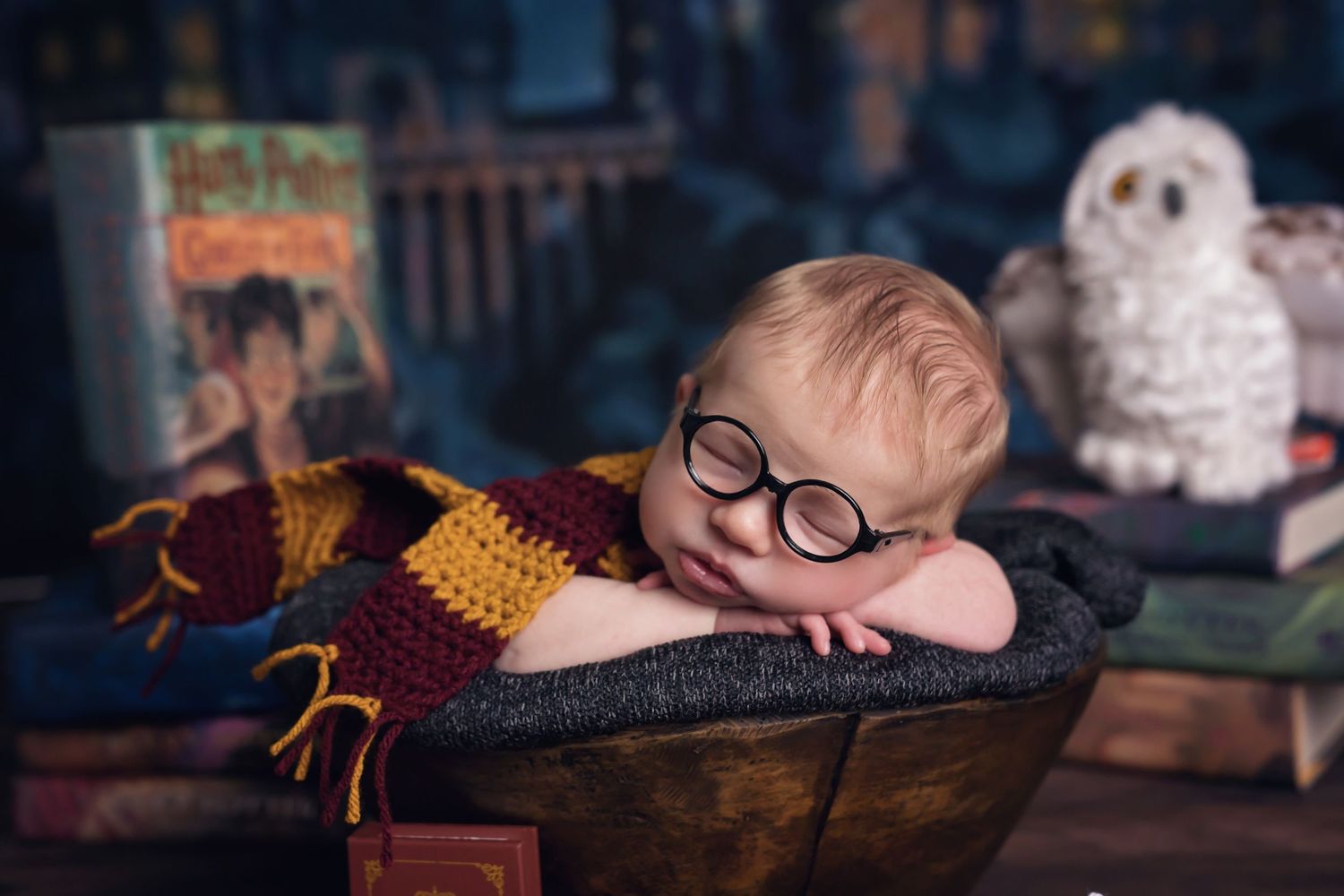 Sleeping baby posed with glasses in a cozy dark setting. San Diego Newborn Photographer