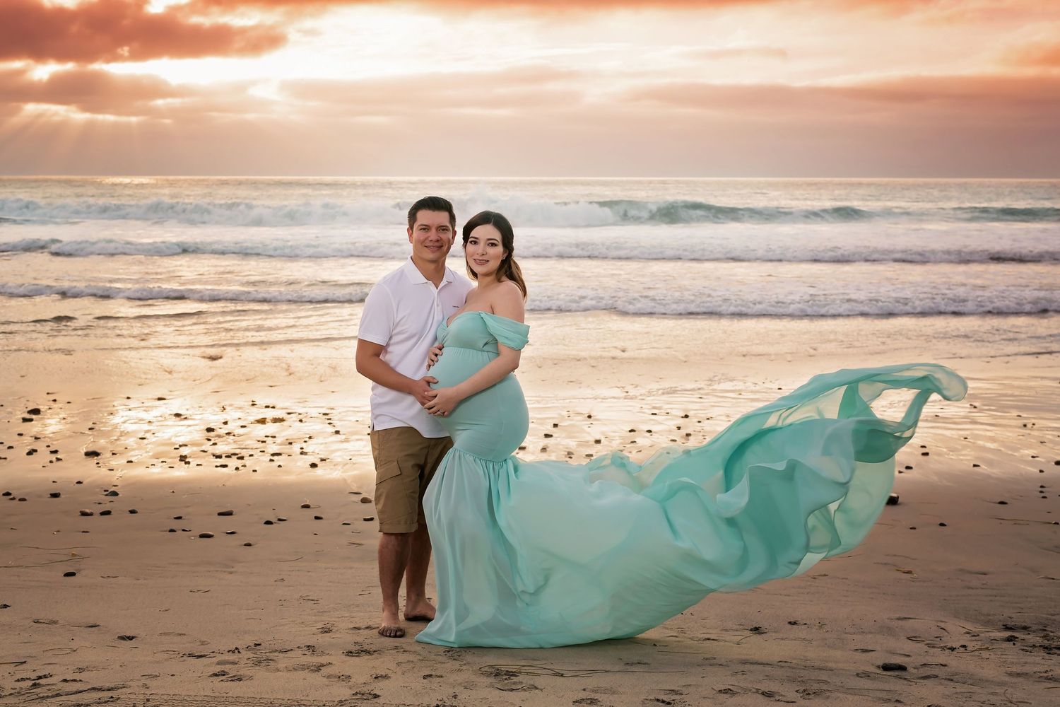 Beach maternity portrait with flowing seafoam dress catching wind during golden hour. San Diego Maternity Photographer