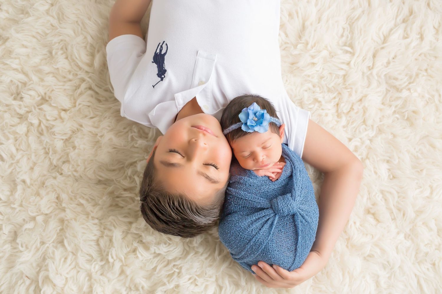 Newborn baby wrapped in white fabric lying on cream textured background in multiple artistic poses. San Diego Newborn Photographer