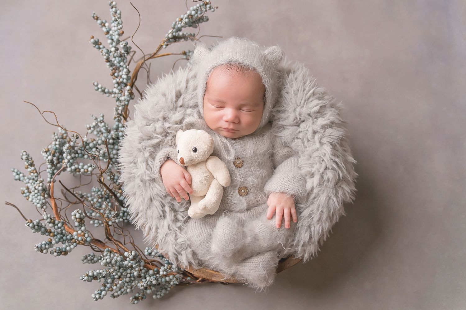 Newborn photography session with soft gray fur blanket and delicate floral decorations. San Diego Newborn Photographer
