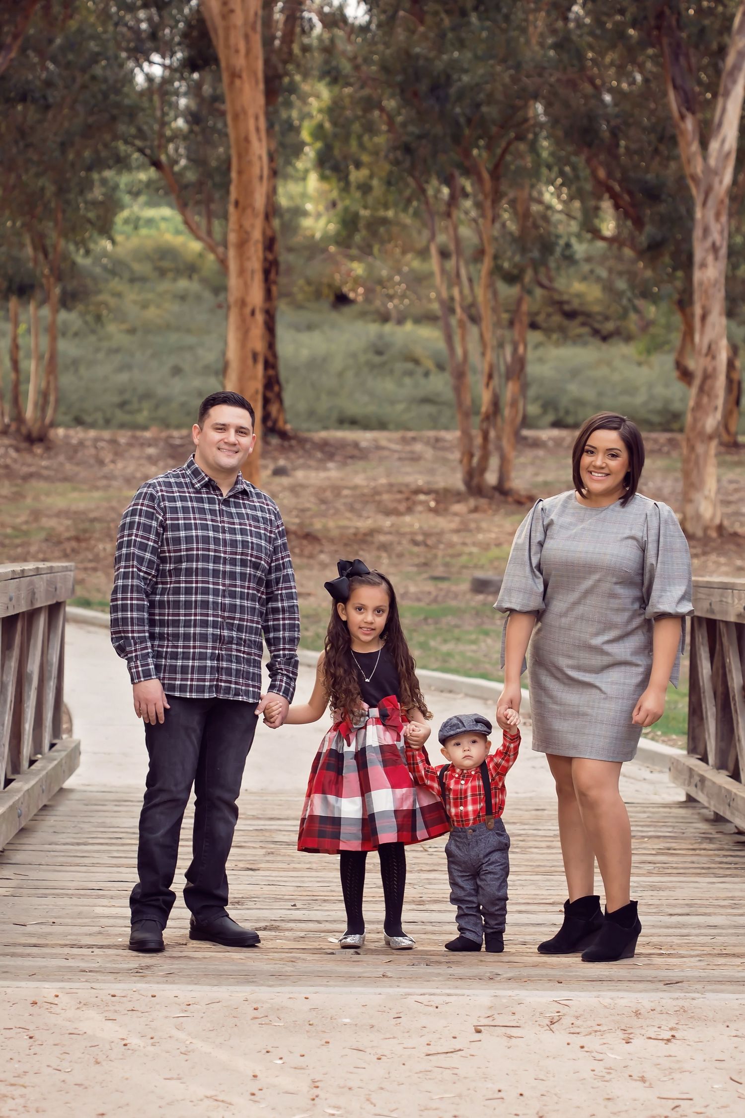 Family posing together on a wooden walkway surrounded by eucalyptus trees in a casual outdoor shoot