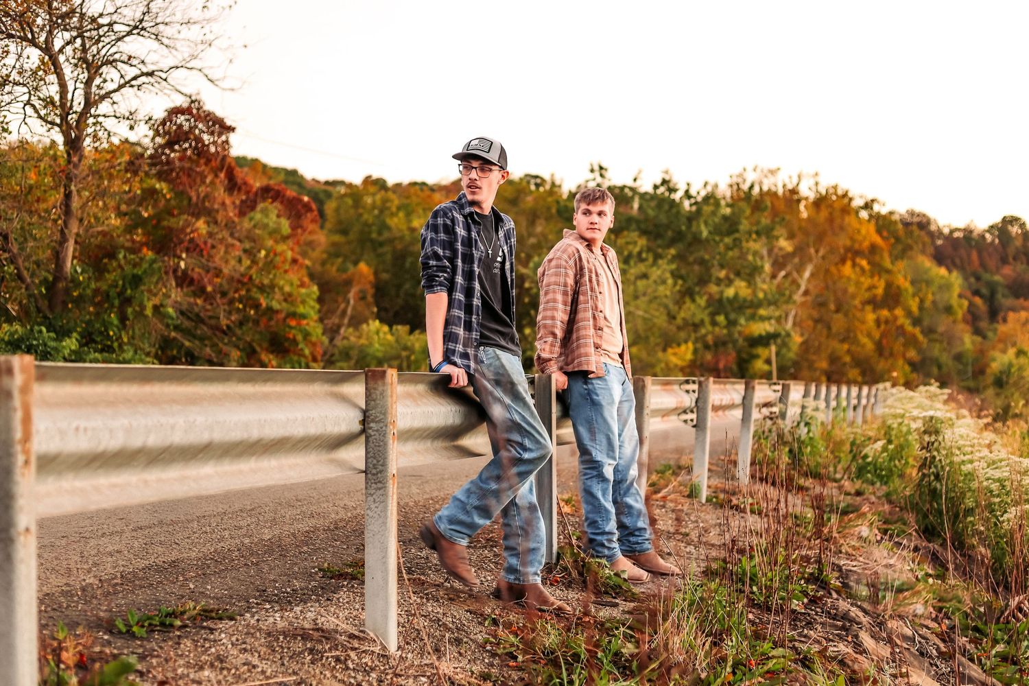 two young men along a road barrier