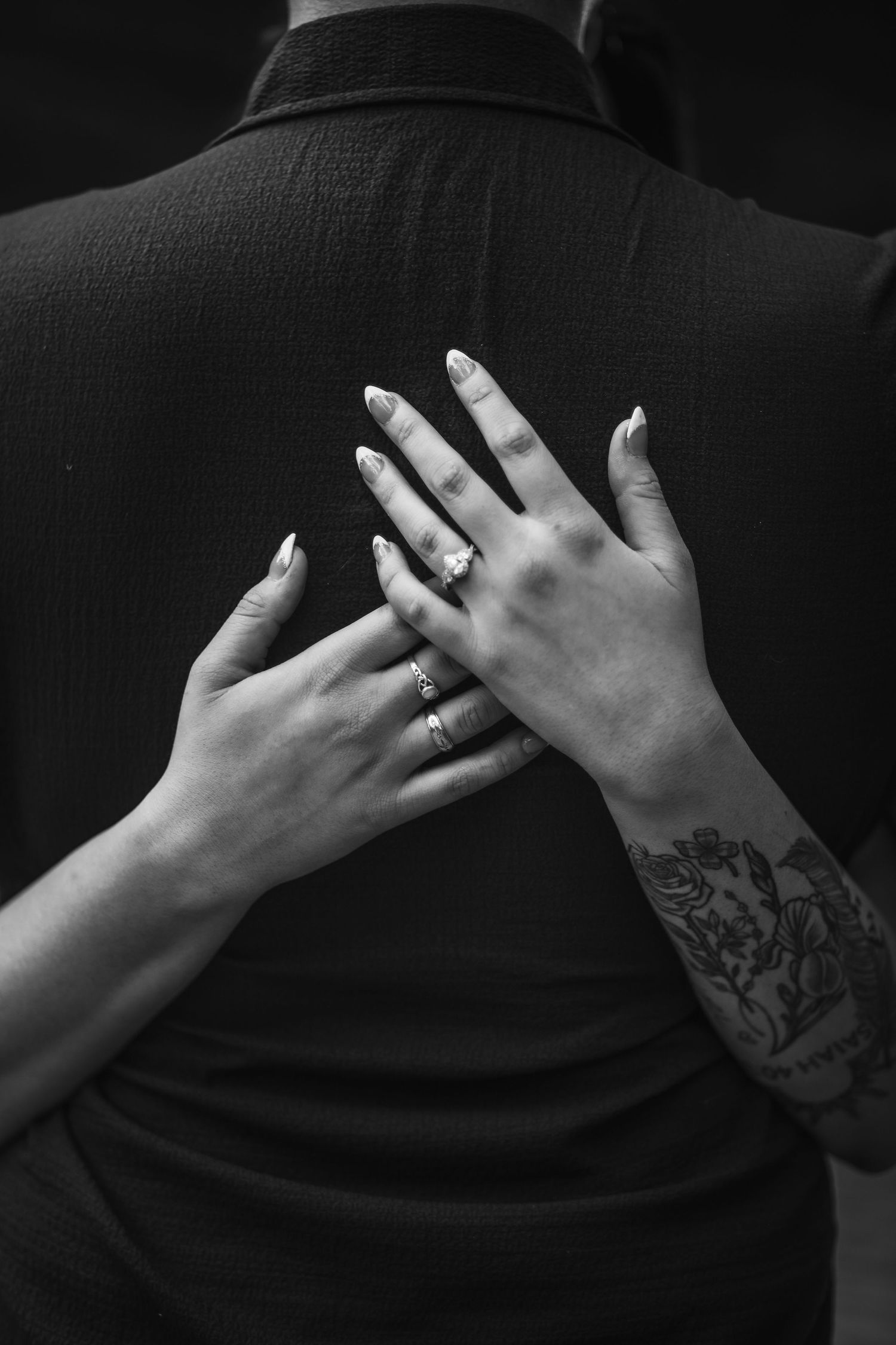 Black and white photography of an engagement ring during a hug.
