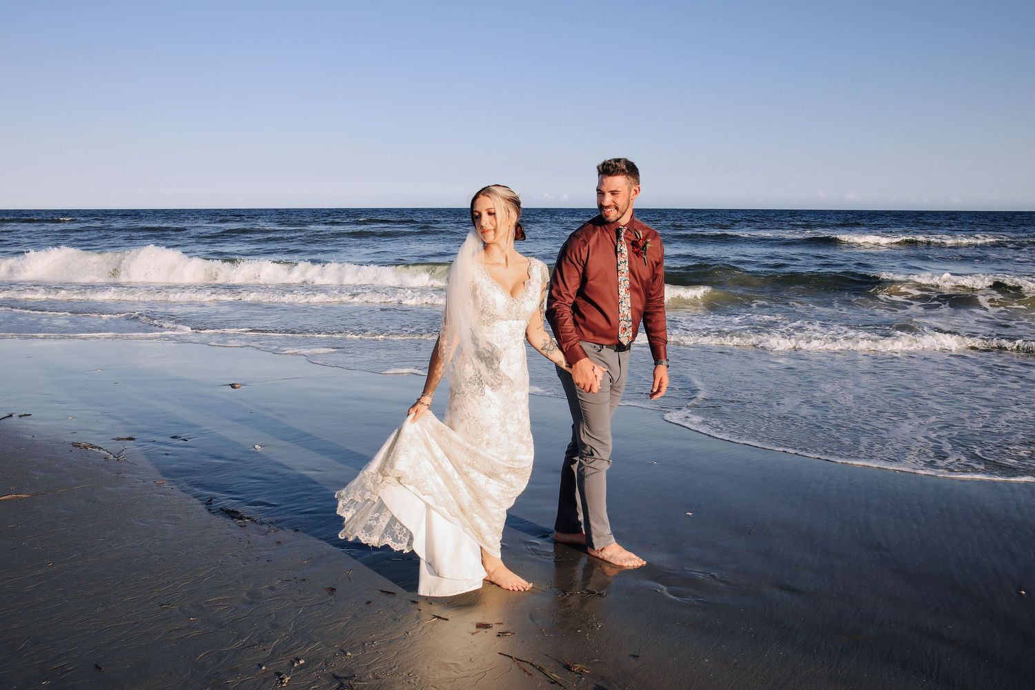 Newly married couple walks along the beach to celebrate and take photographs.