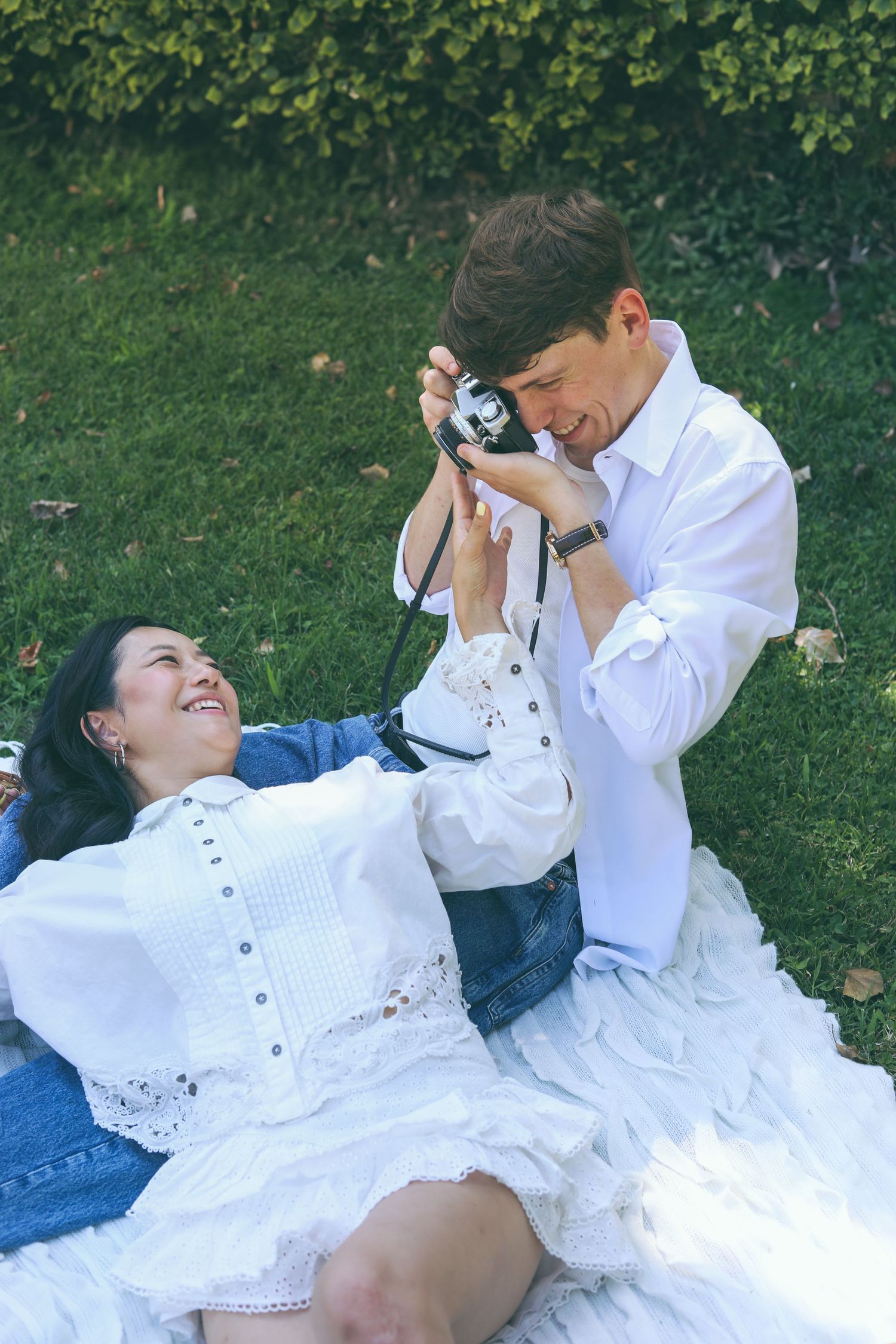A young couple photographing each other on a picnic