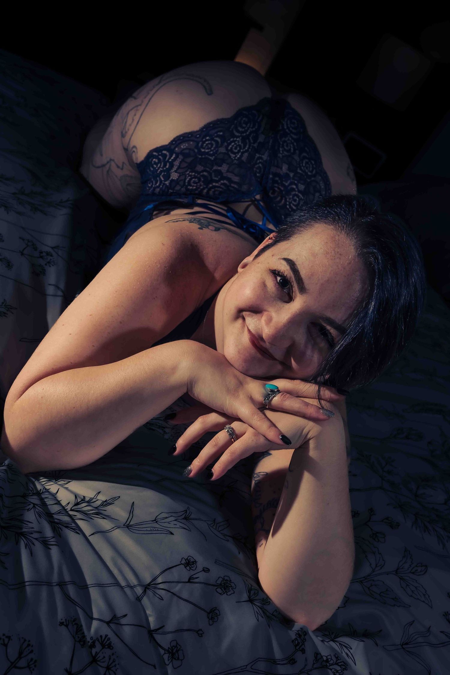 Boudoir photo with a model laying down on a bed and smiling
