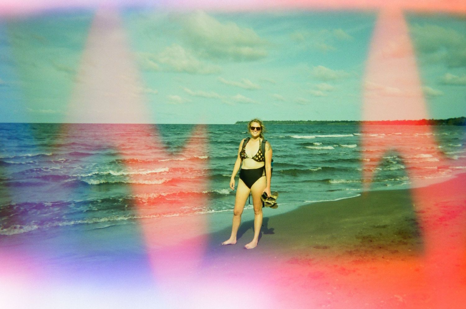 Beach scene with colorful light leaks and ocean waves in the background.