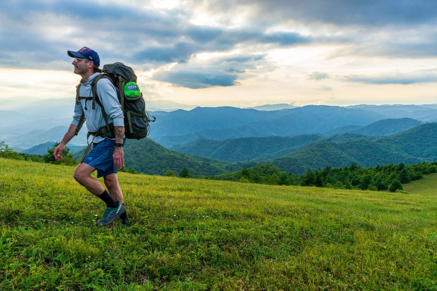 Grassy hilltop trail with expansive mountain views in the distance.