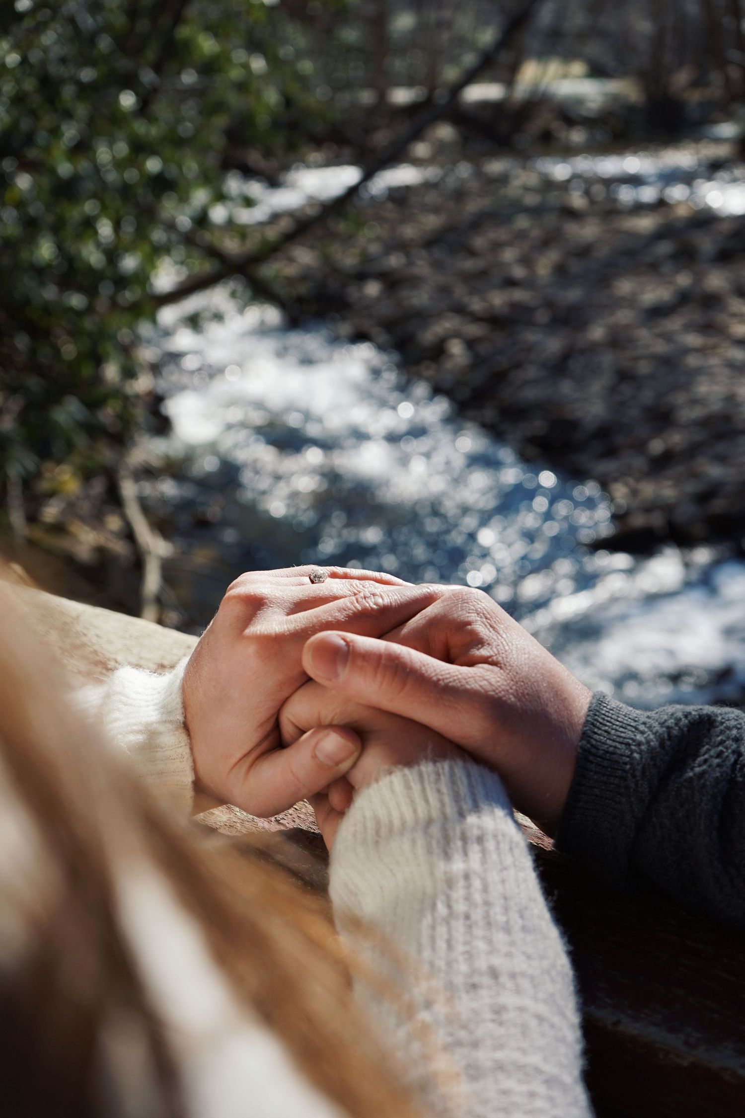 Close-up shot of hands gently touching while wearing cozy winter sweaters outdoors.
